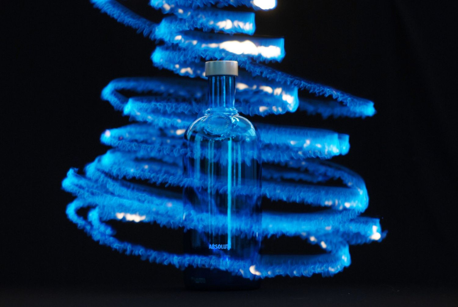 A bright blue spiral pattern of light creates a glowing helix shape against a dark background.