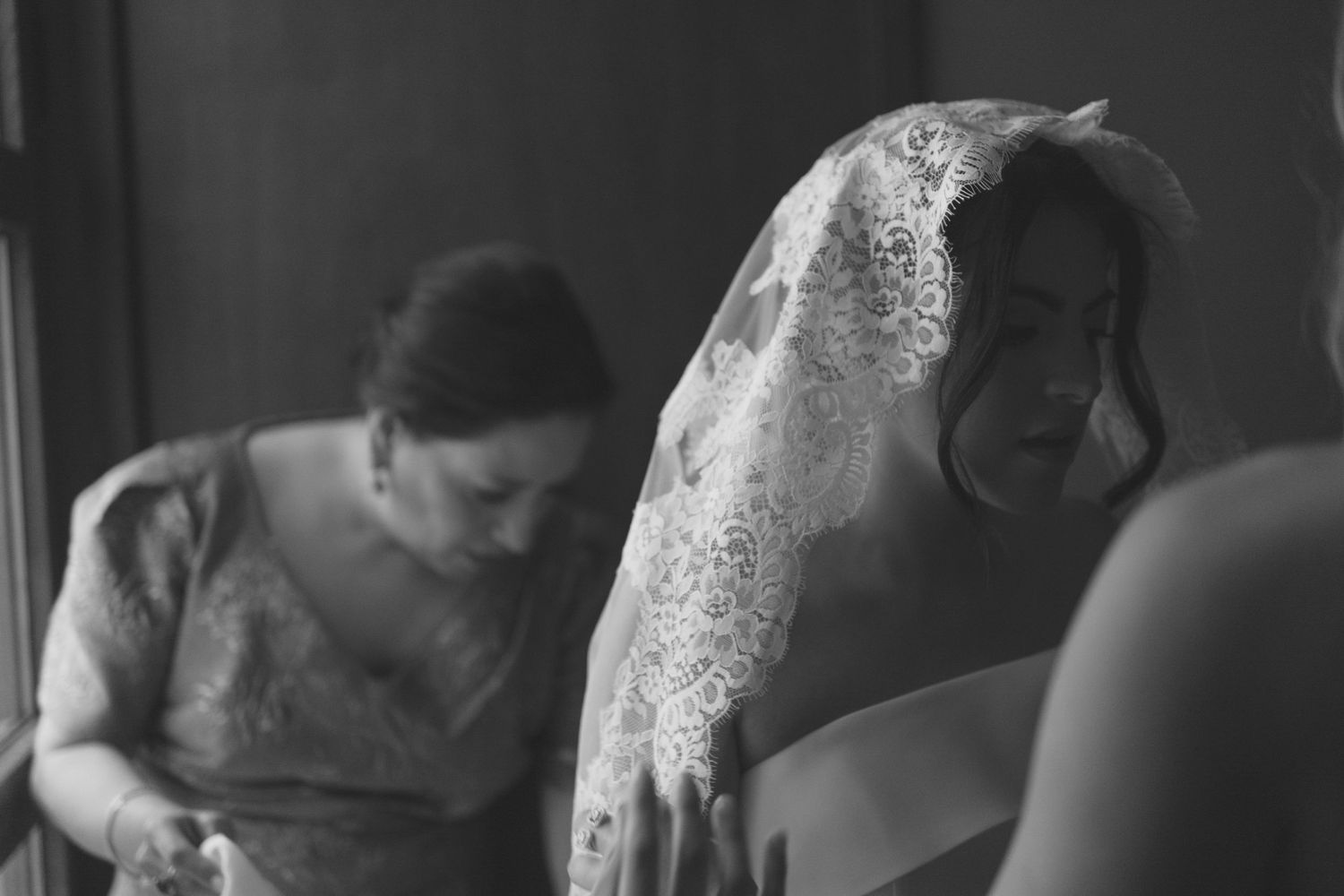 Black and white image of people preparing for wedding ceremony.