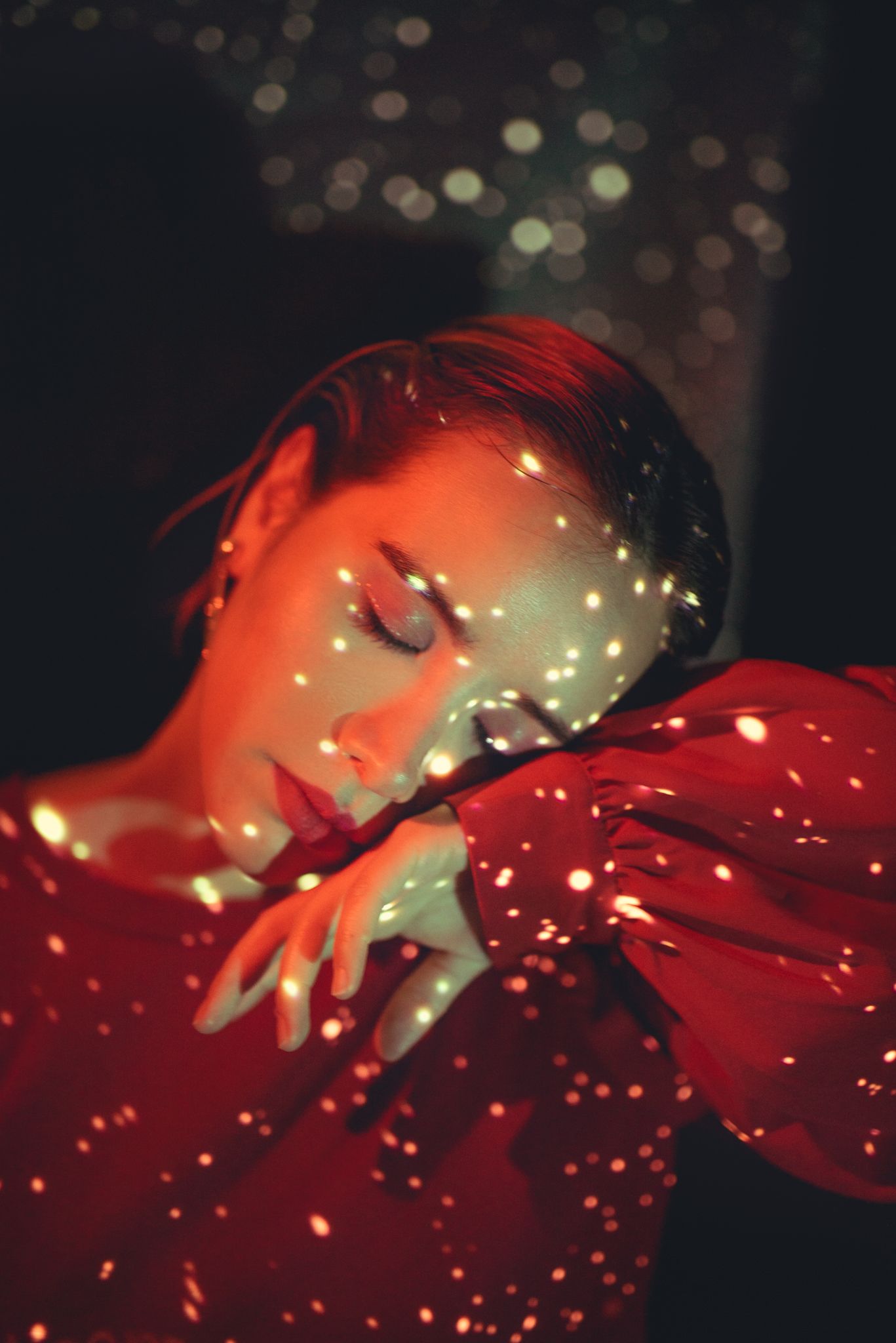 Dreamy portrait with sparkly light effects and red lighting creating a magical atmosphere.