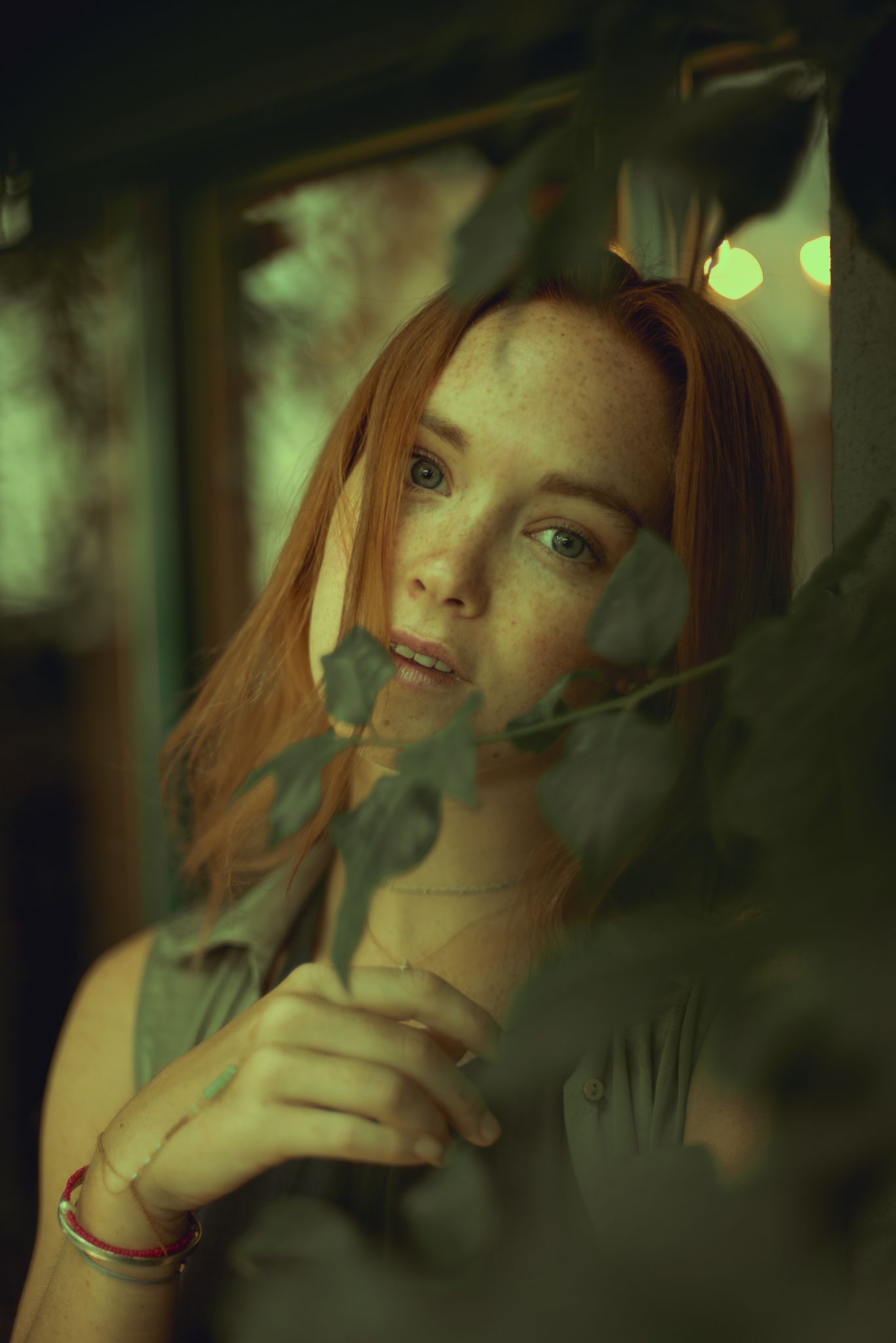 Moody portrait with plants and green lighting creating mysterious atmosphere.