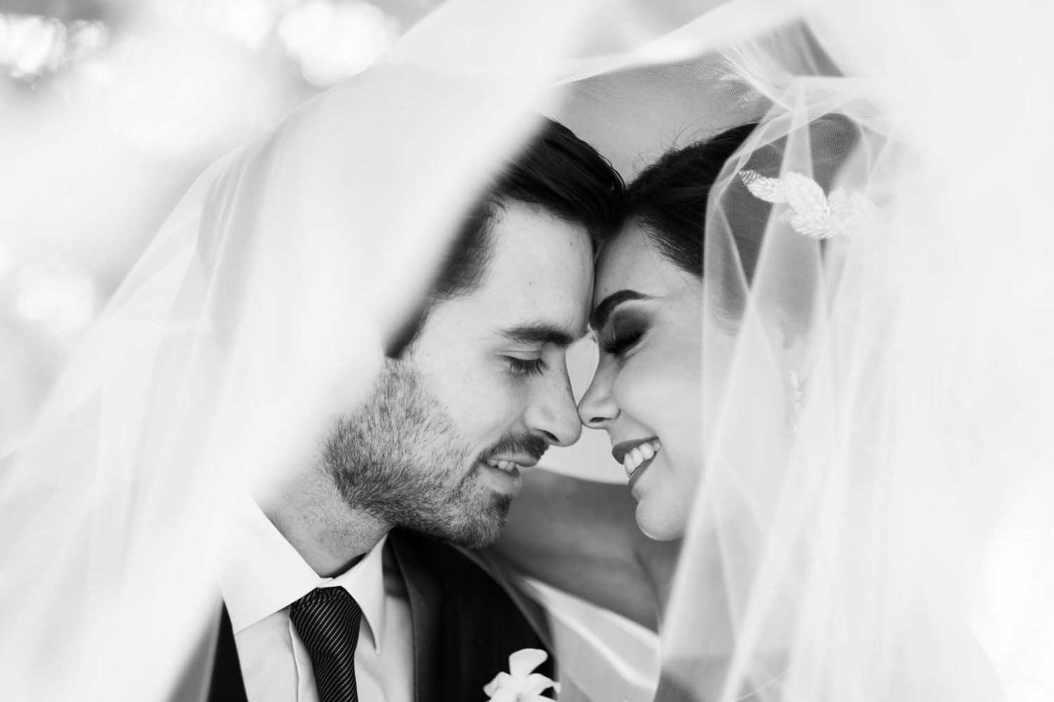 A black and white intimate moment captured under flowing wedding veil.