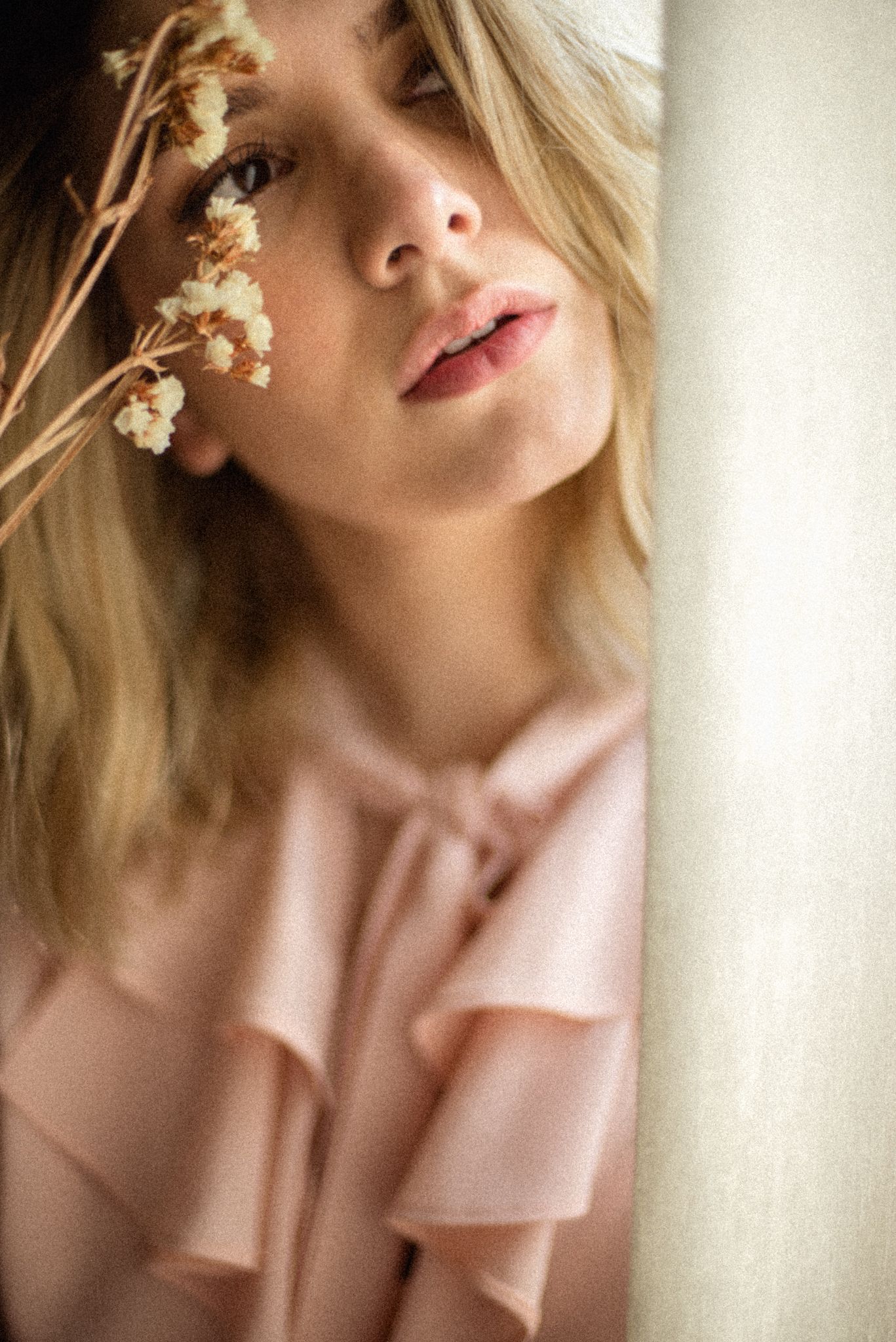 Dreamy portrait with dried flowers and soft window lighting.