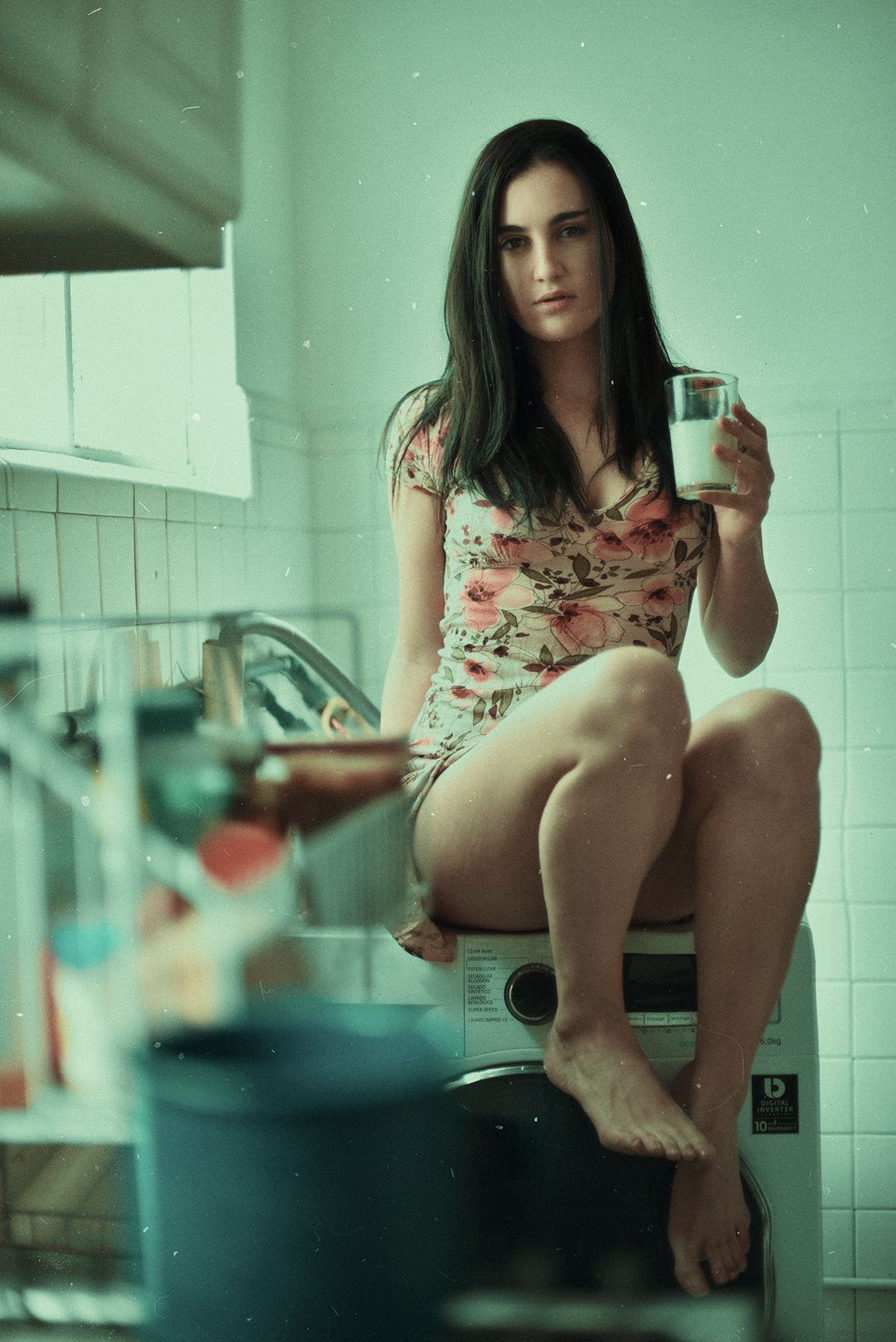 Person in floral dress sitting casually in bathroom with minimal decor.