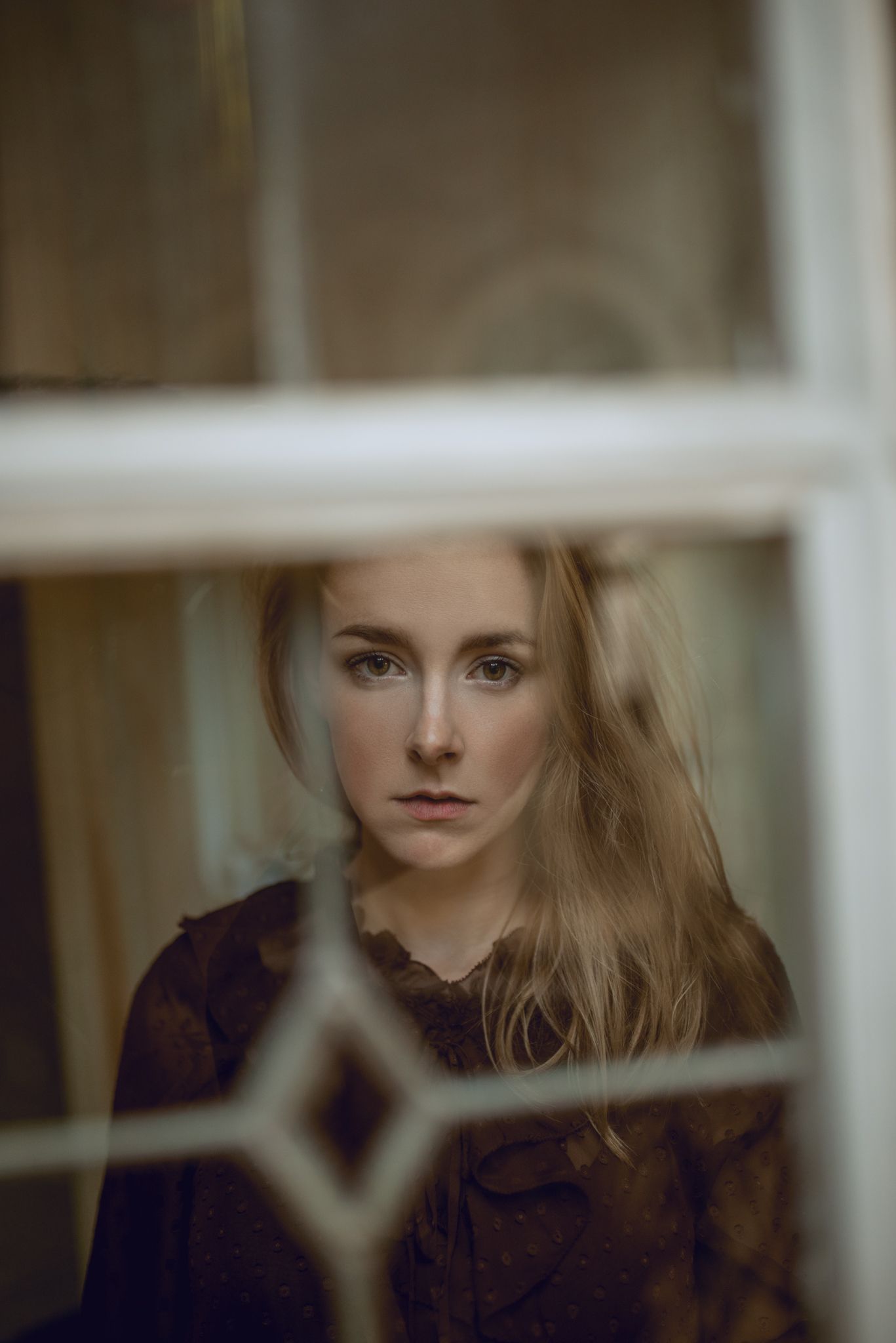 Portrait through window pane with shallow depth of field.