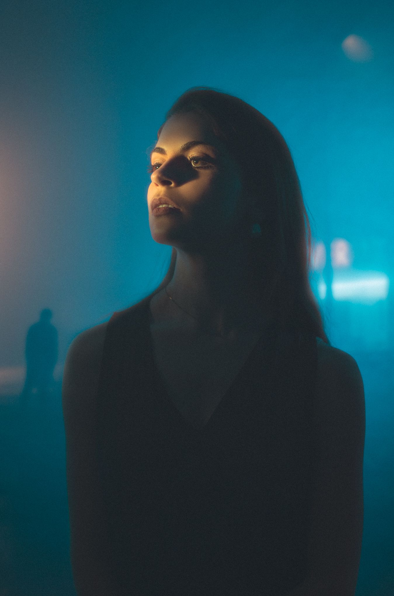 Atmospheric portrait with blue ambient lighting and misty background.