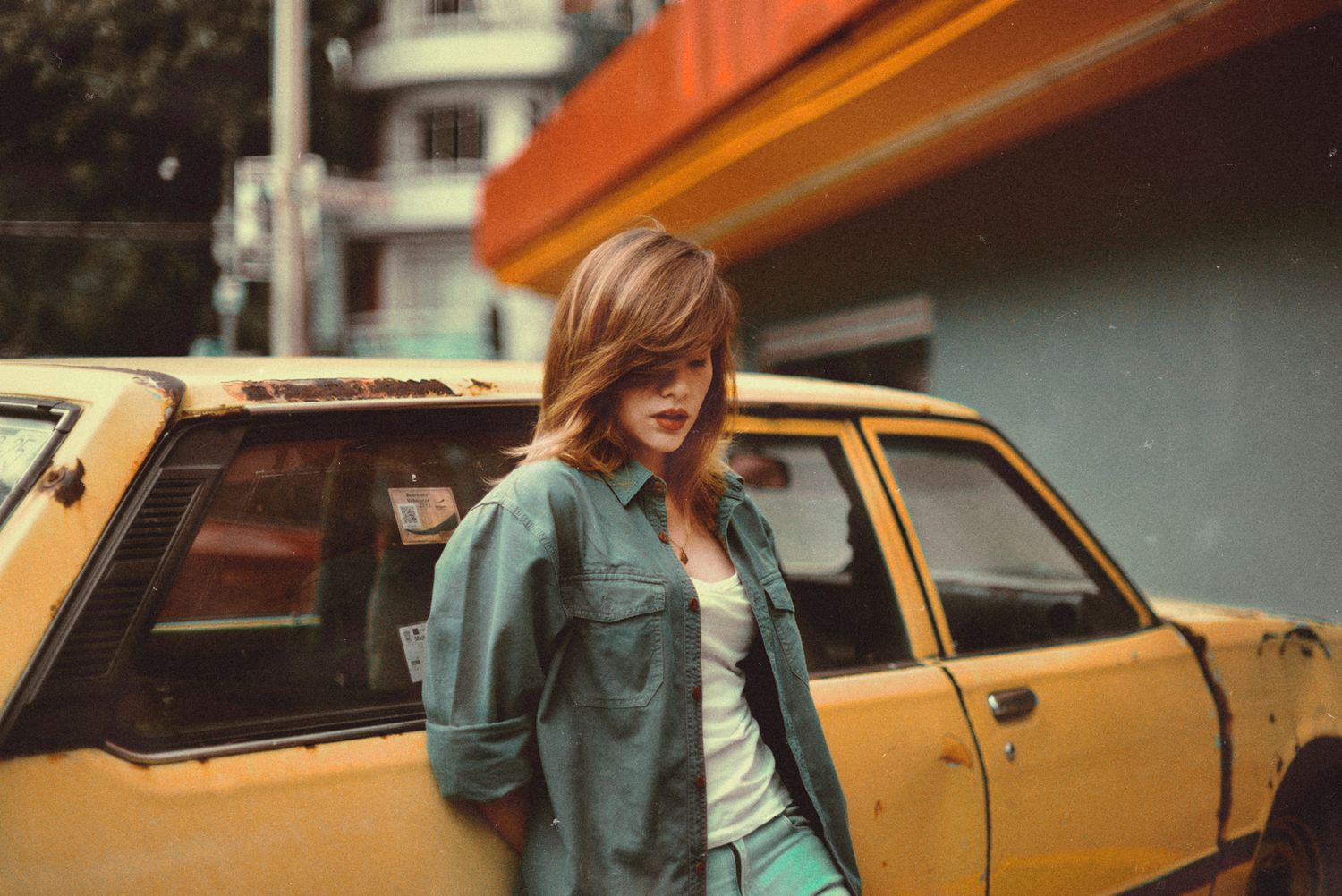 Casual style portrait next to yellow vintage car on urban street.