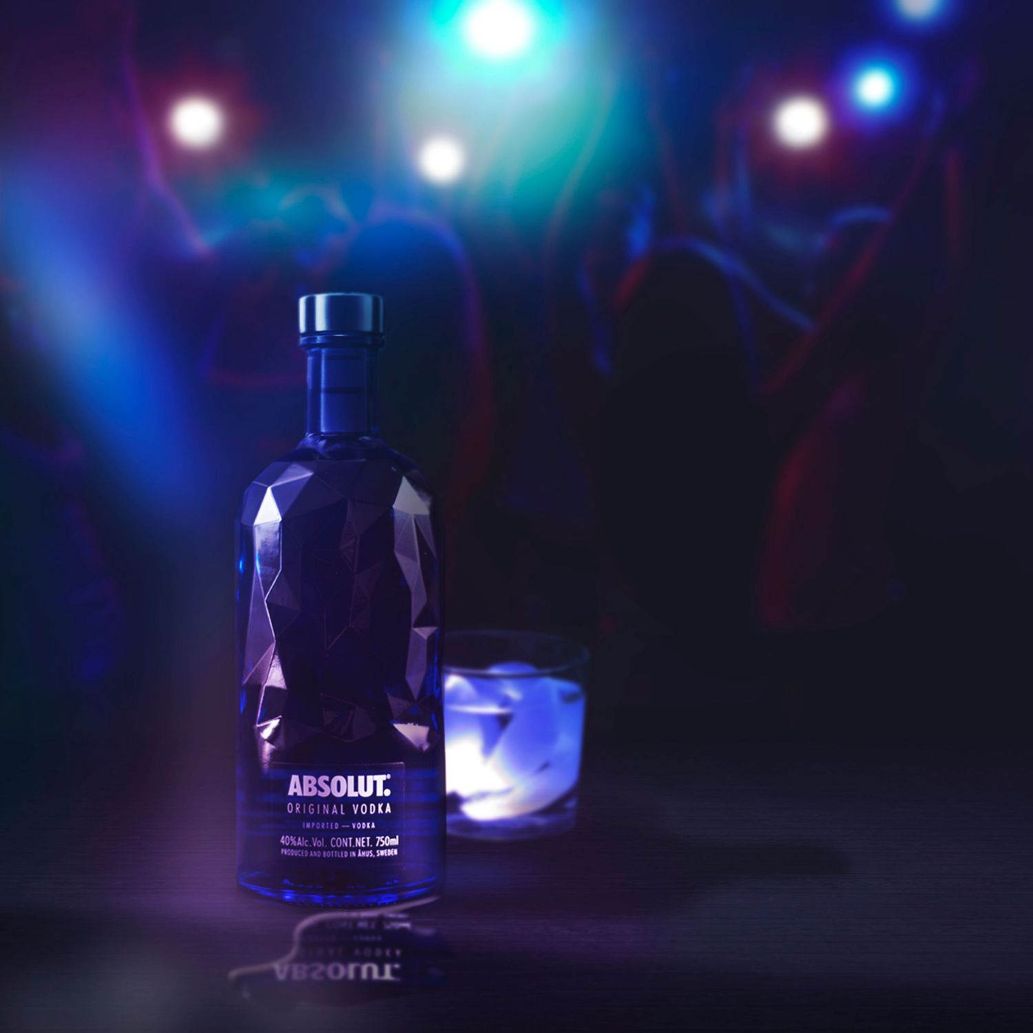 A series of Absolut vodka bottles arranged in dark nightclub lighting with glowing blue and purple ambient effects.