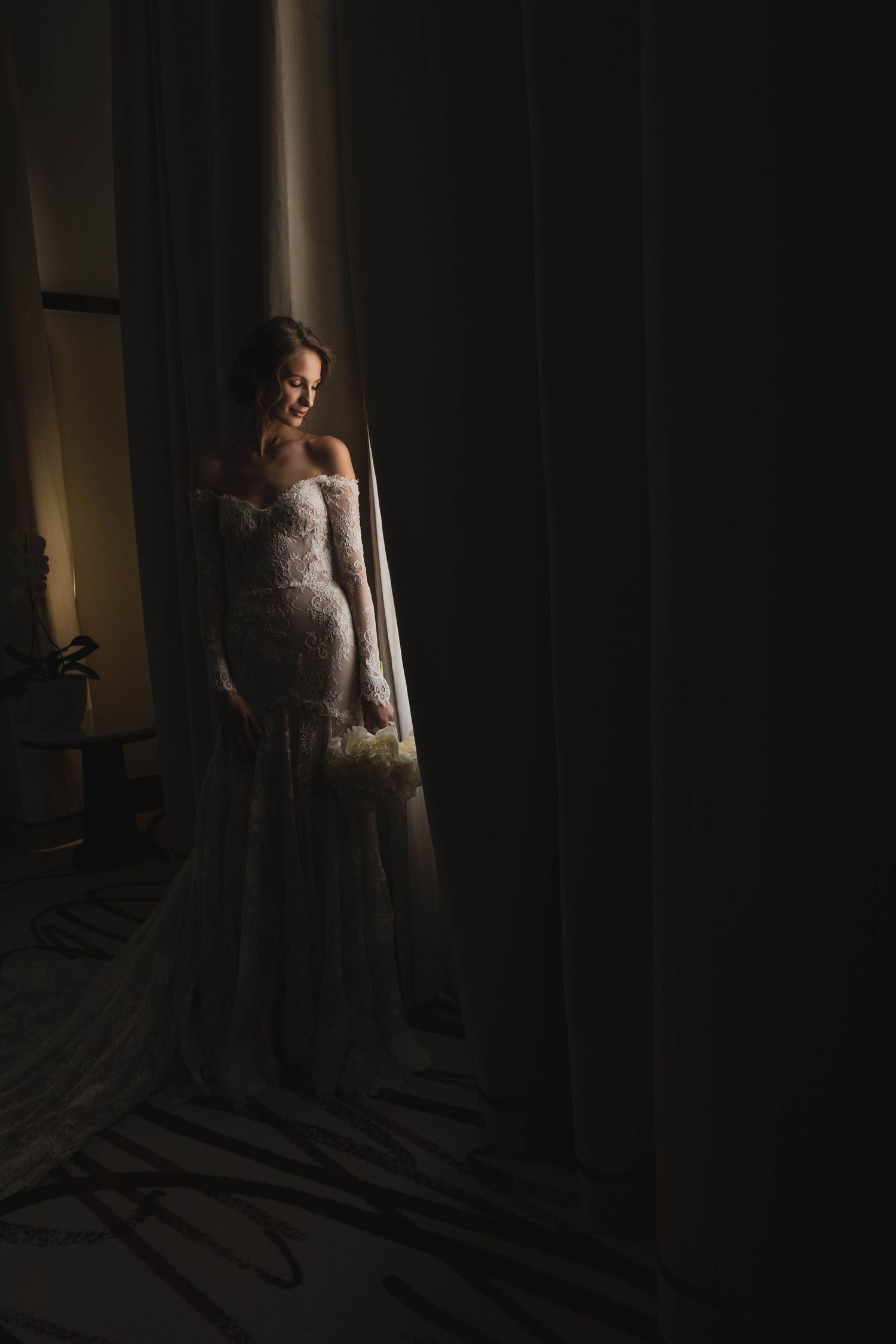 Dramatic shadow play captures a wedding dress silhouette near a window.