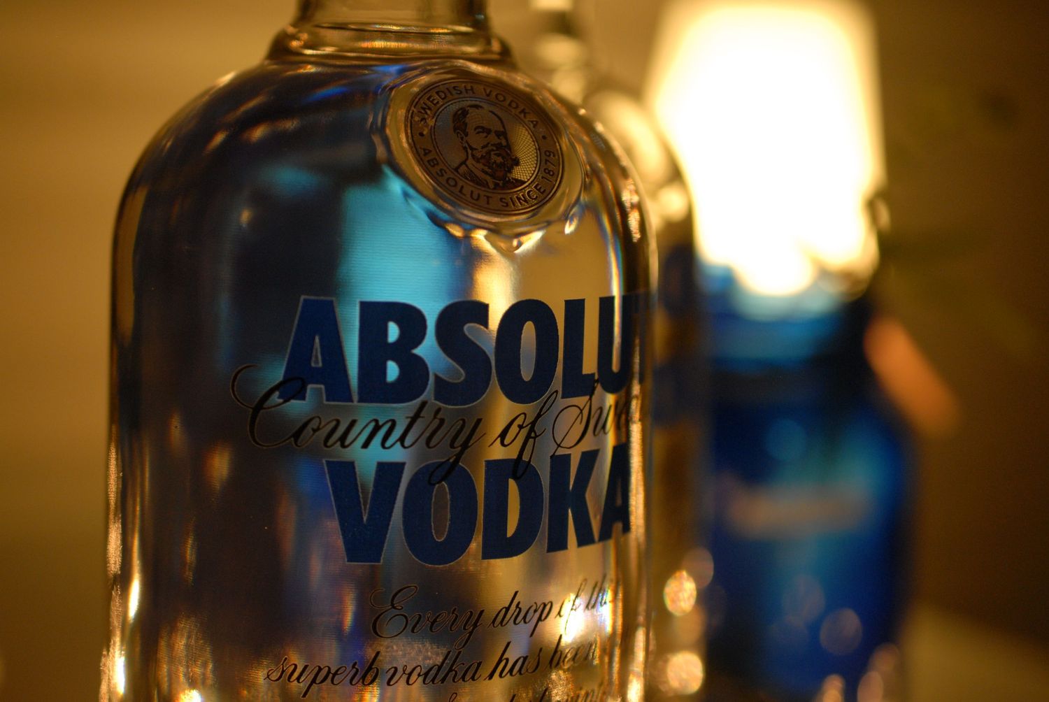 Close-up shot of an Absolut Vodka bottle label with warm ambient lighting.