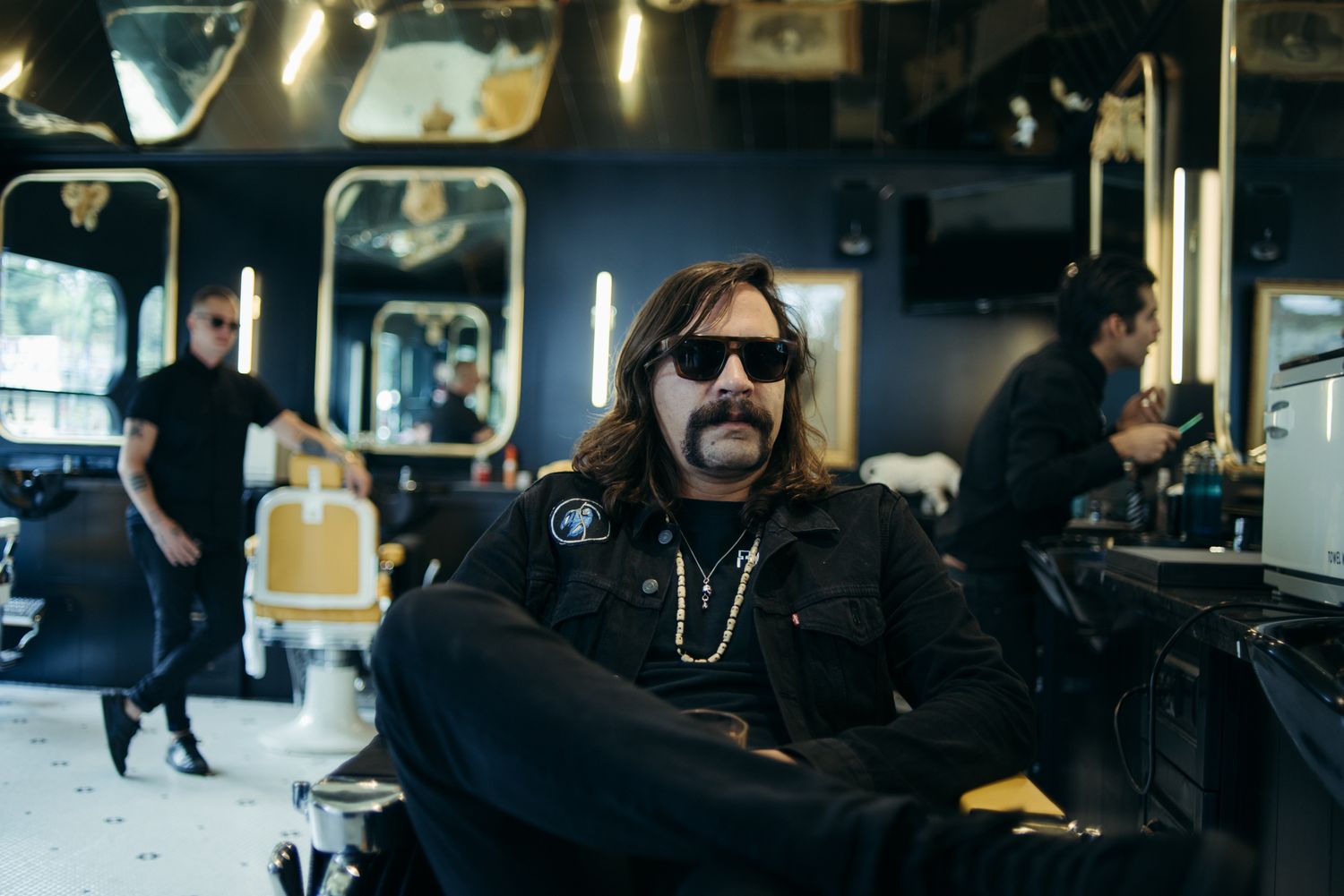 Person in black clothing and sunglasses relaxing in salon chair.