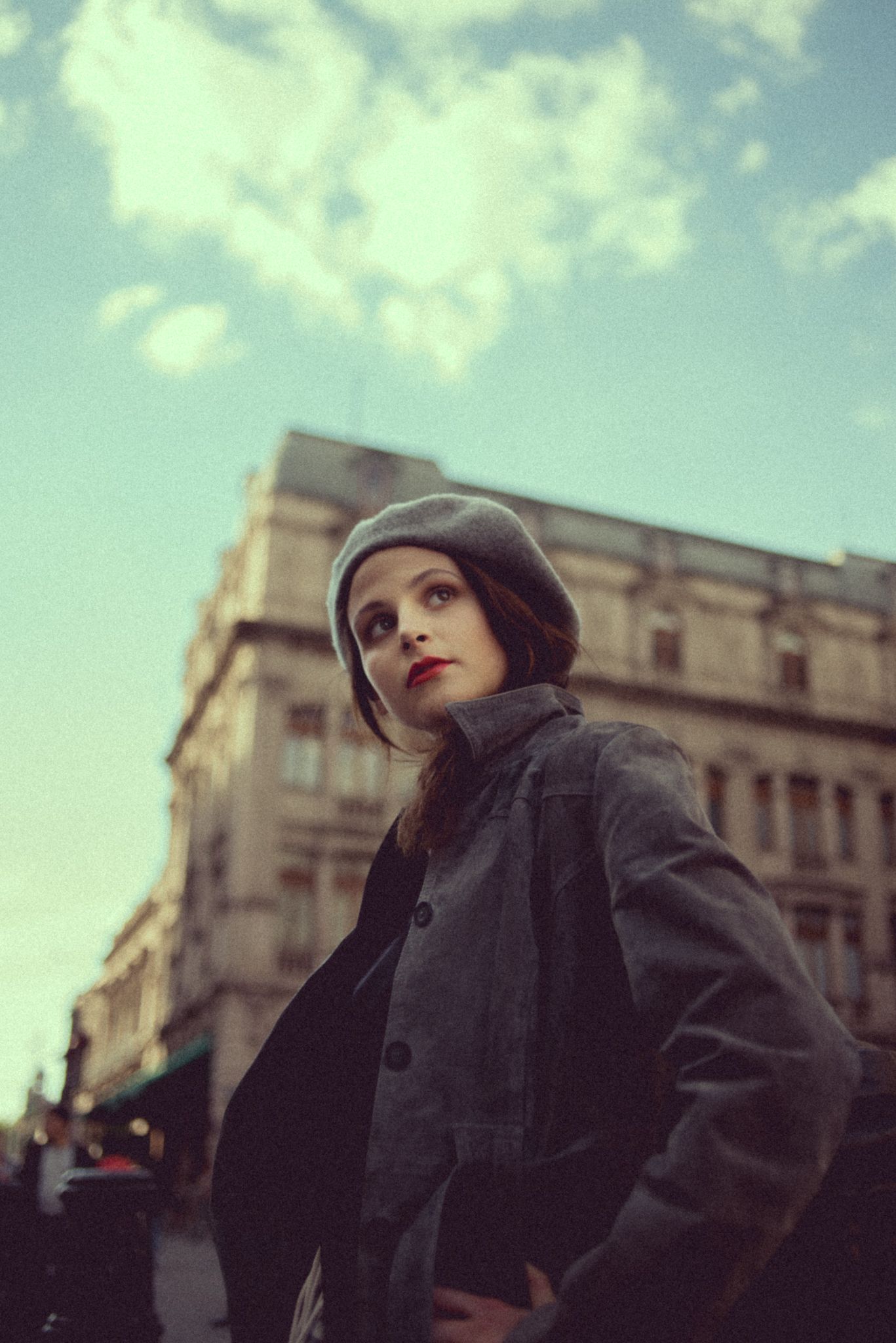 Vintage-style fashion portrait against classic architecture with moody winter sky.