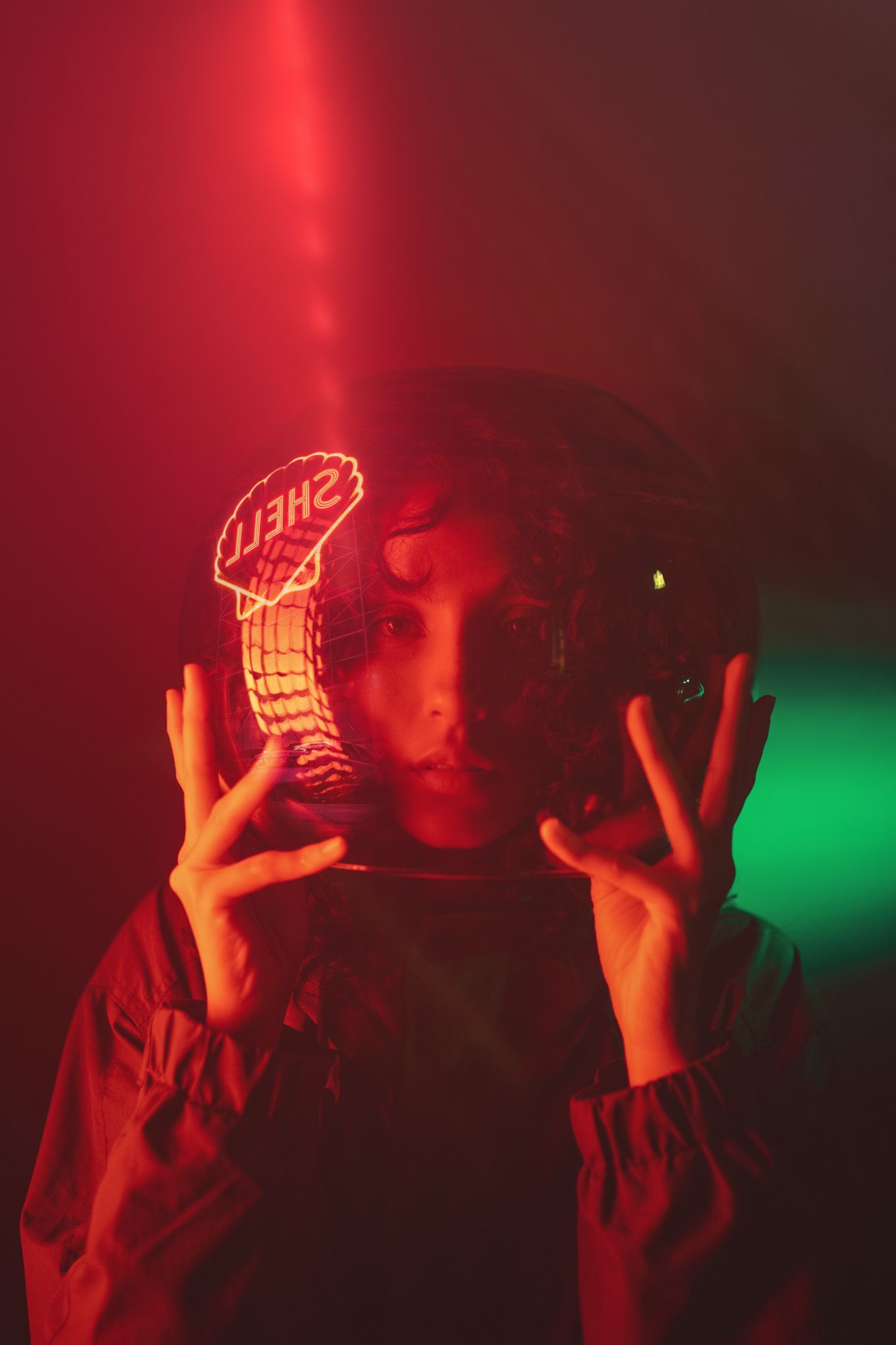 Figure holding mirror ball with red and green lighting creating dramatic reflections.