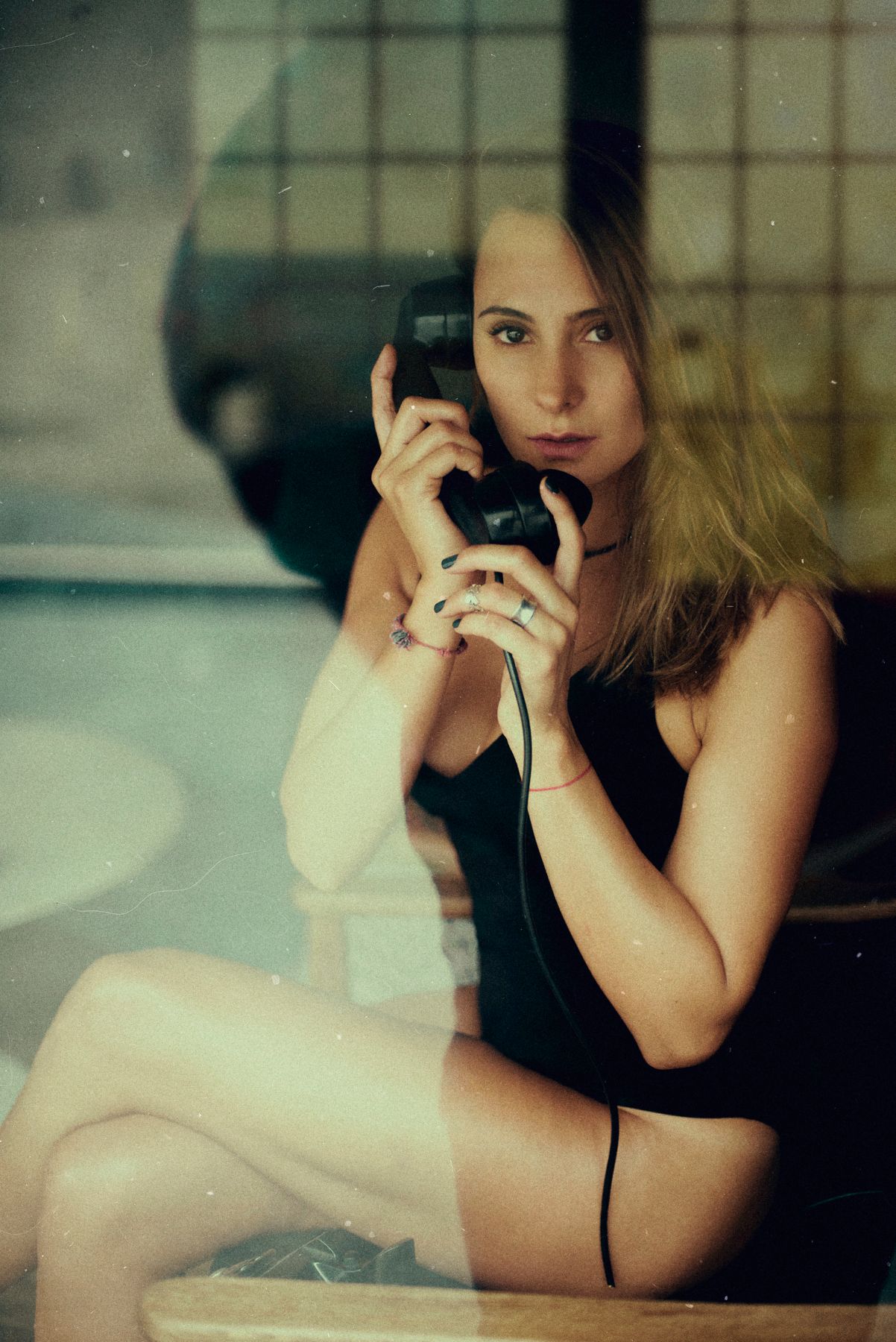Retro-styled portrait of woman using vintage telephone in intimate boudoir setting.