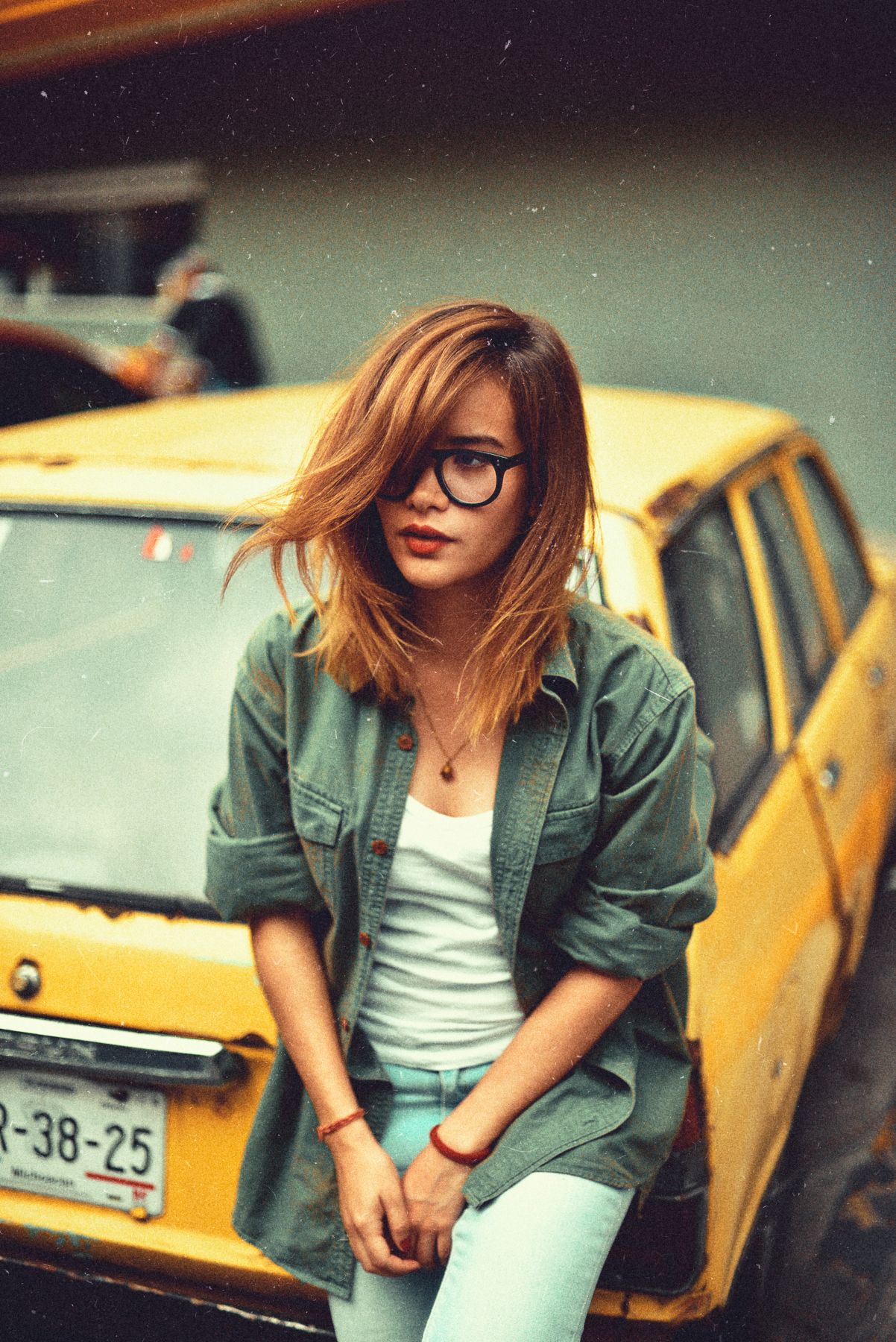 Casual portrait in denim jacket leaning against yellow taxi cab.