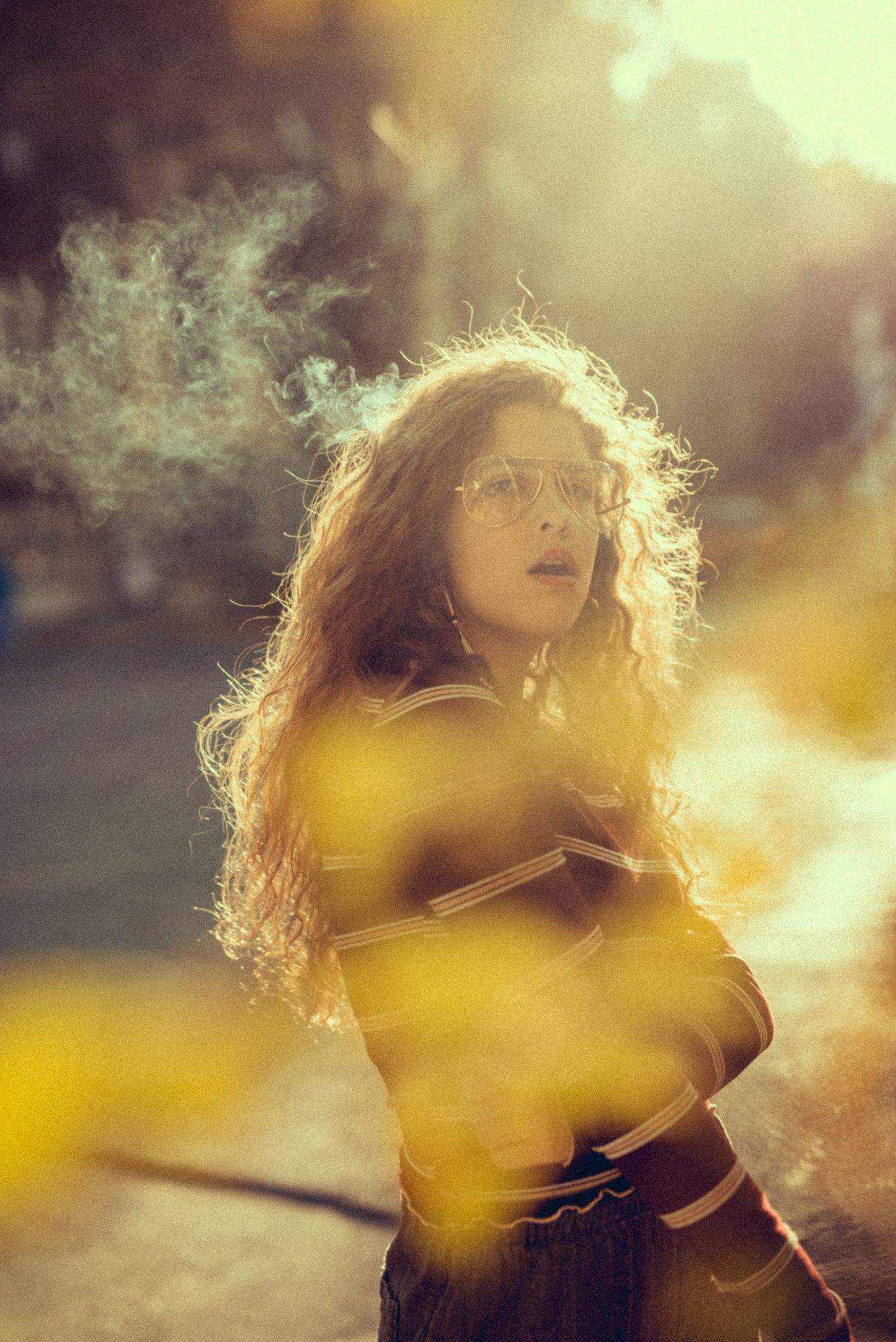 Dreamy outdoor portrait with smoke effects and golden sunlight bokeh.