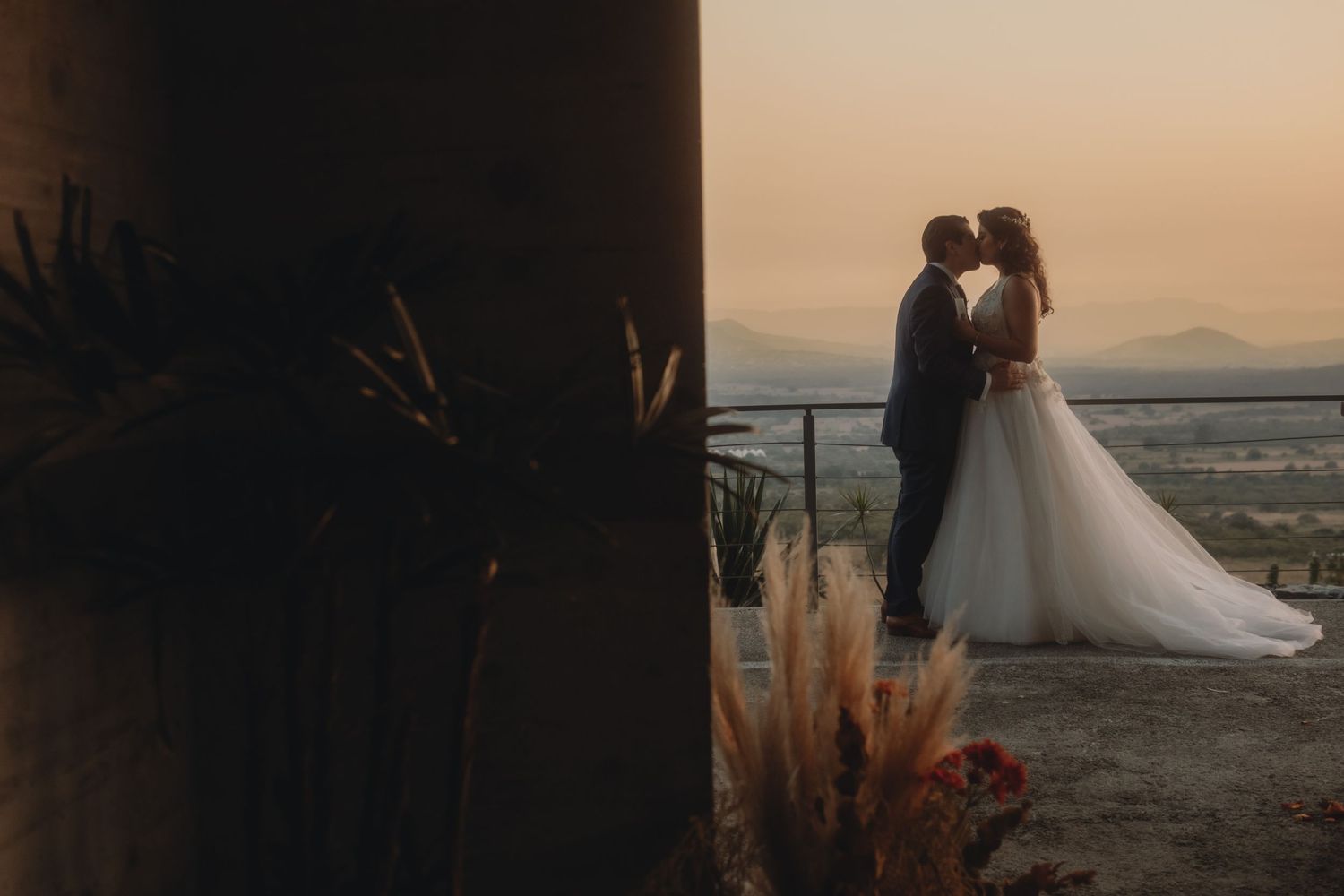 Romantic sunset wedding portrait with desert landscape and mountains in background.