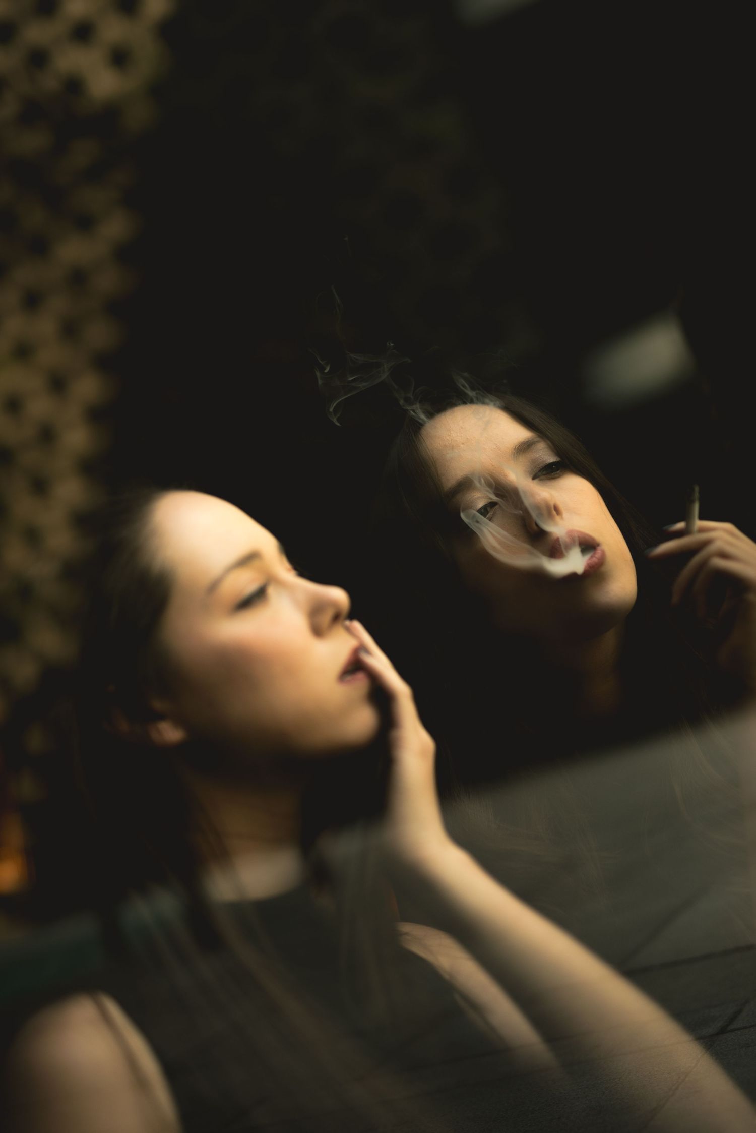 Atmospheric mirror reflection portrait in dim lighting with smoke effects.