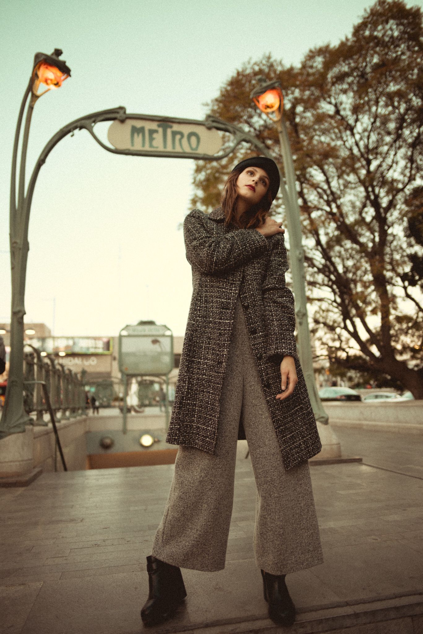 Stylish winter outfit with tweed coat and wide-leg pants under vintage Metro sign.
