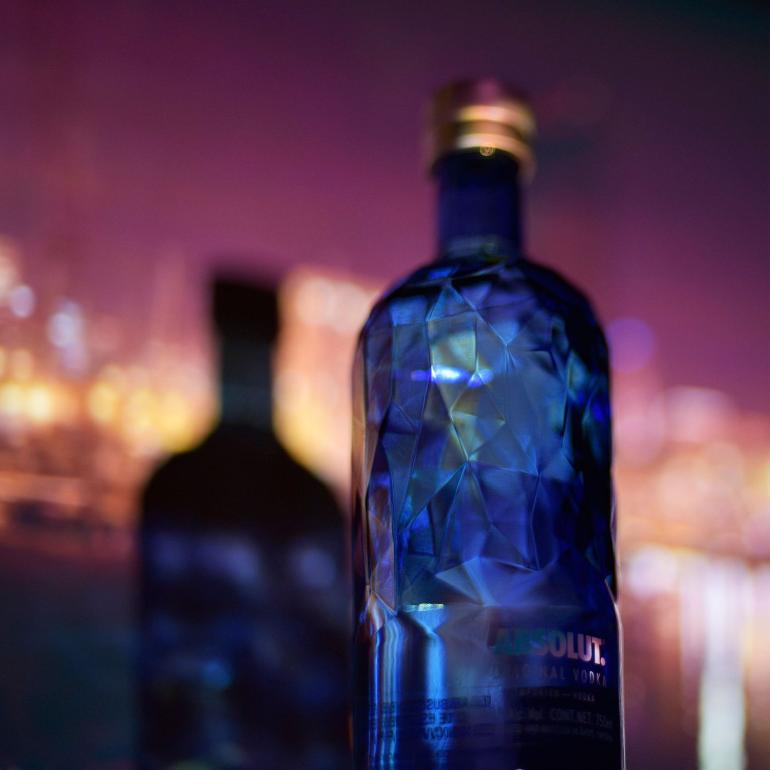 Blue glass bottles silhouetted against a purple sunset create a dramatic bokeh effect.