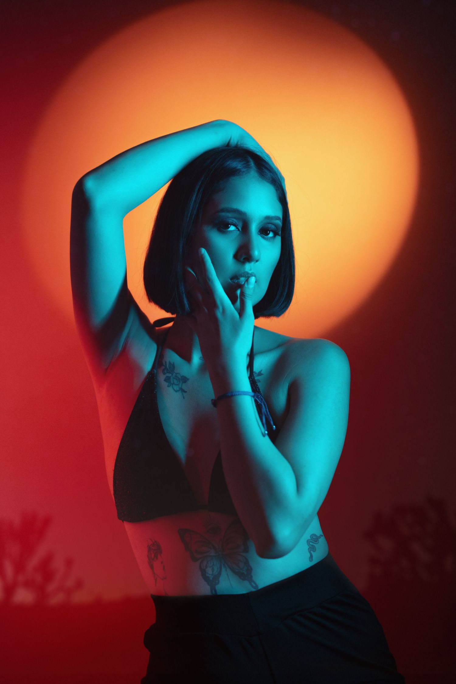 Artistic portrait with dramatic orange and blue lighting effects creating moody atmosphere against dark background.