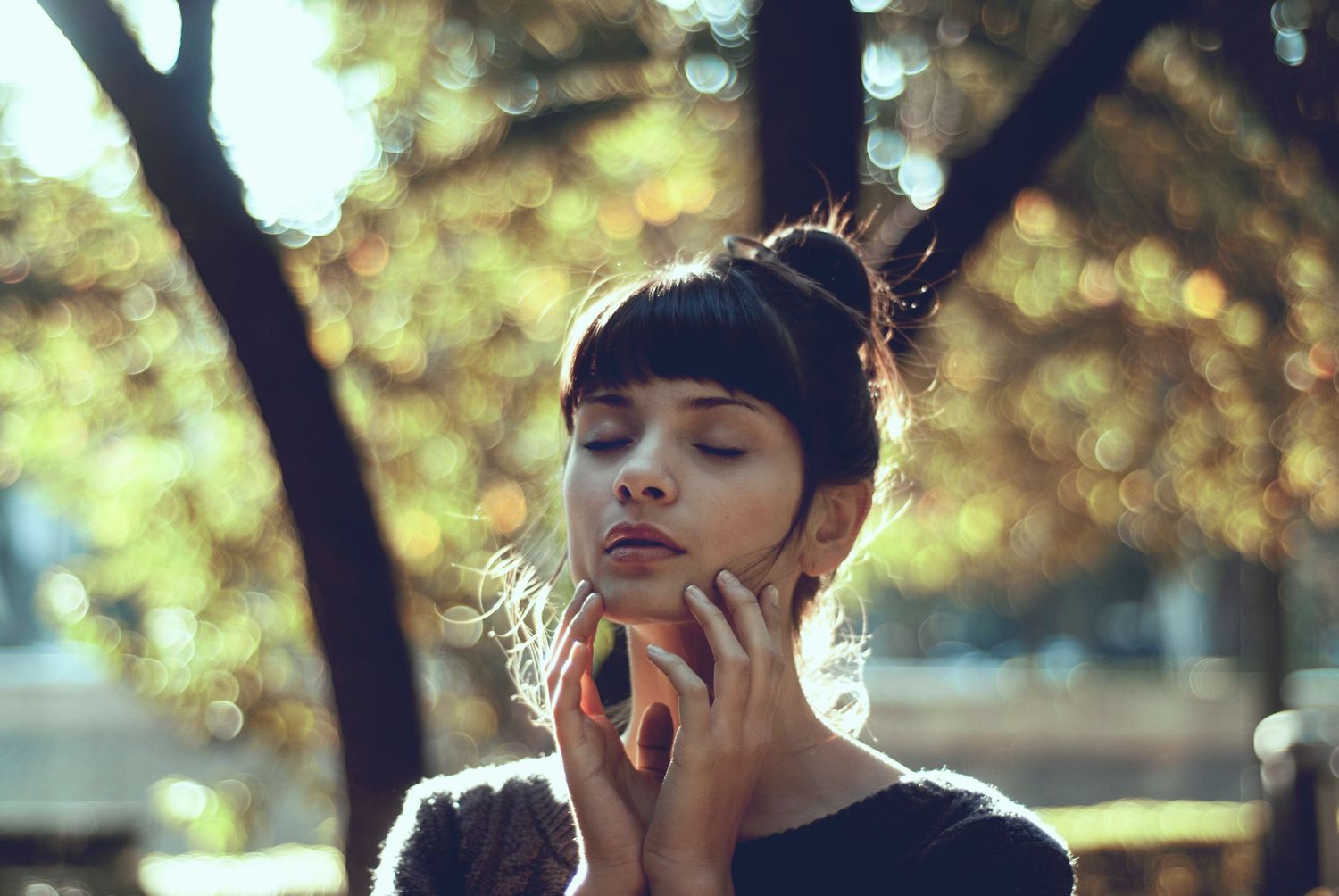 Sunlit portrait with delicate hand gesture and soft natural lighting.