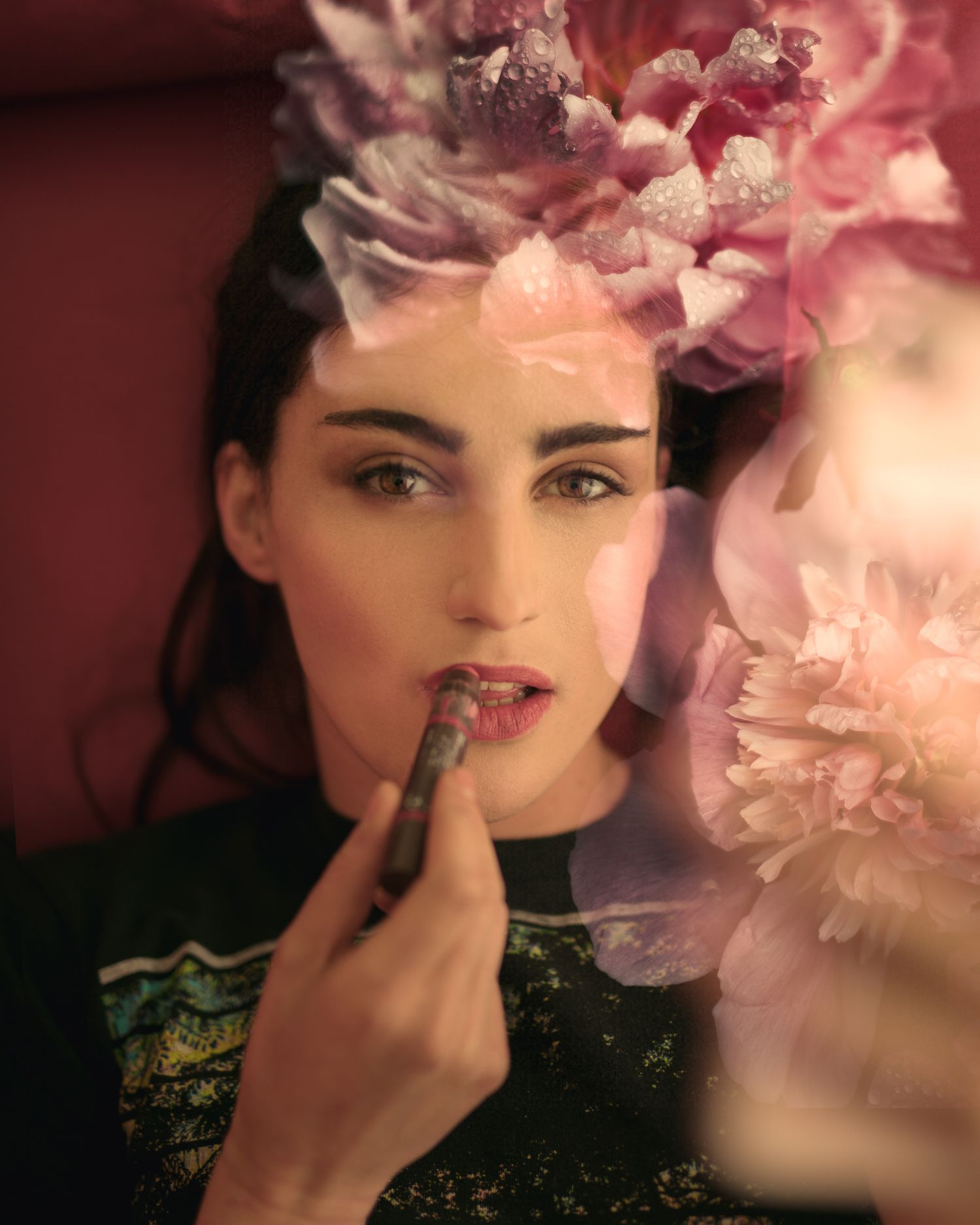 Elegant beauty portrait with pink floral elements and dark green attire.