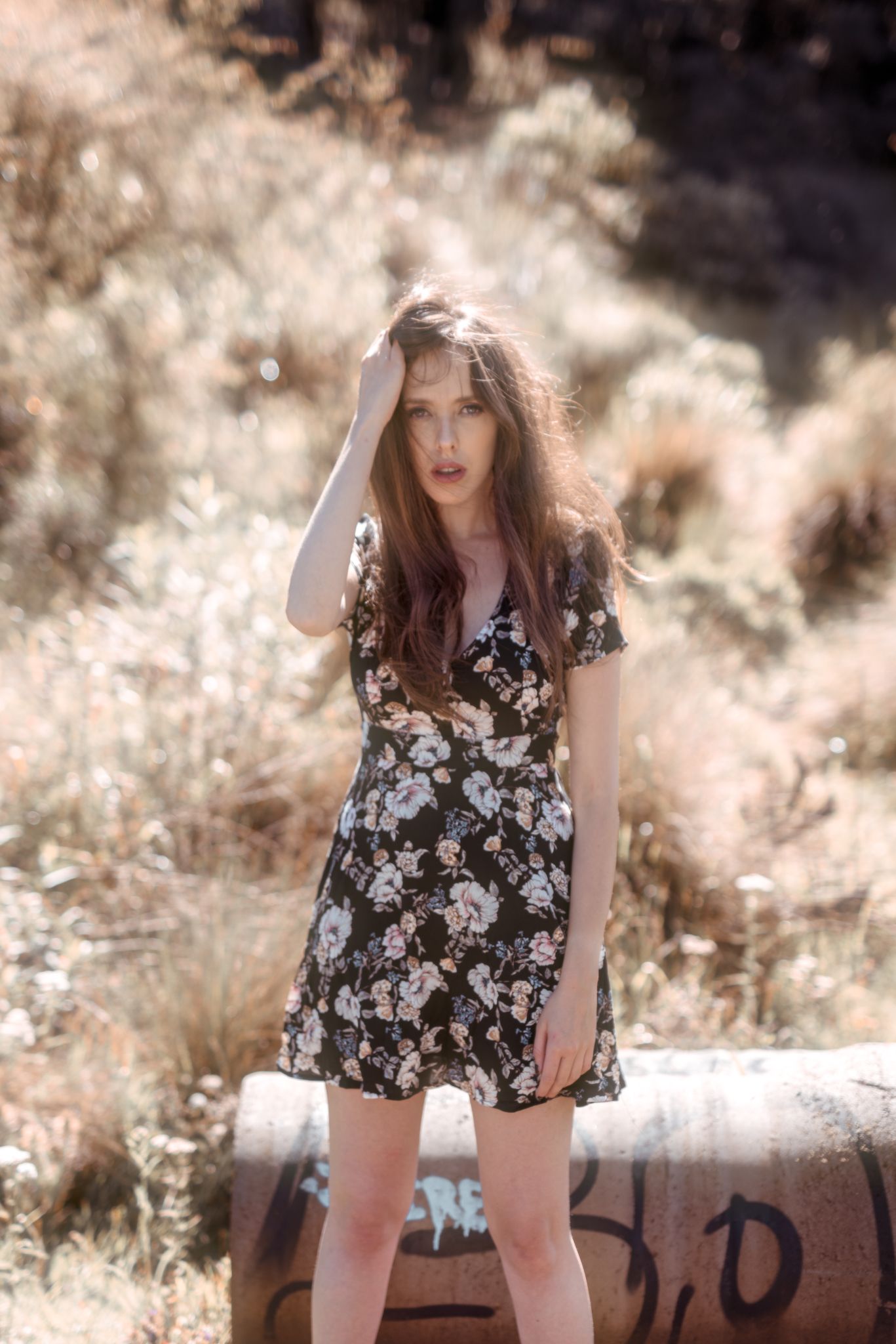 Floral dress portrait in golden sunlit field with artistic dreamy atmosphere.
