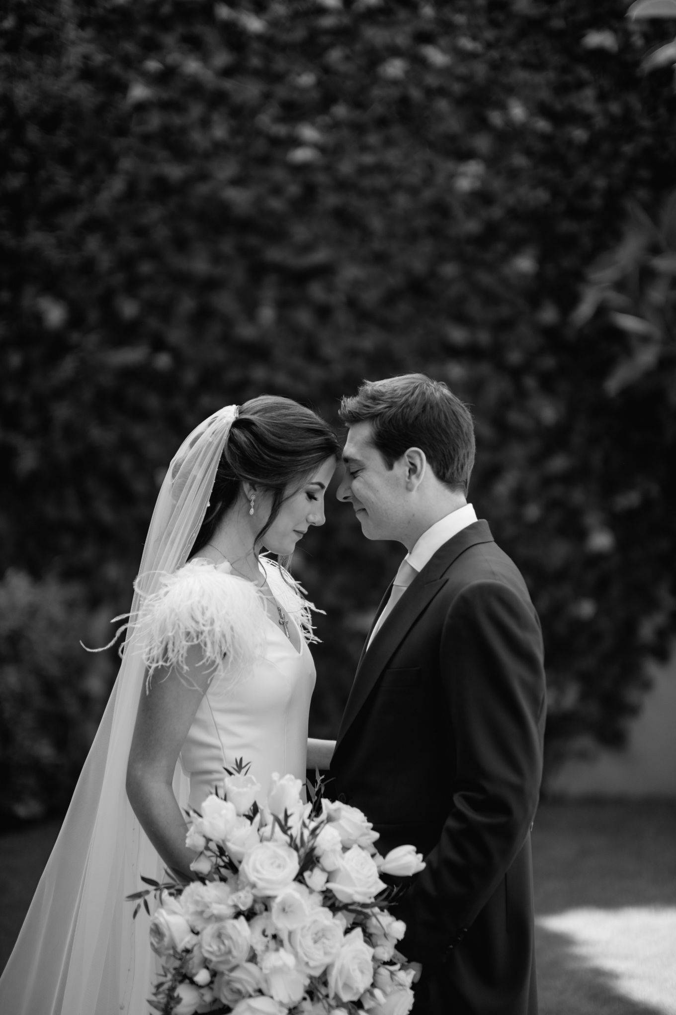 Black and white portrait of newlyweds with bride holding white floral bouquet.