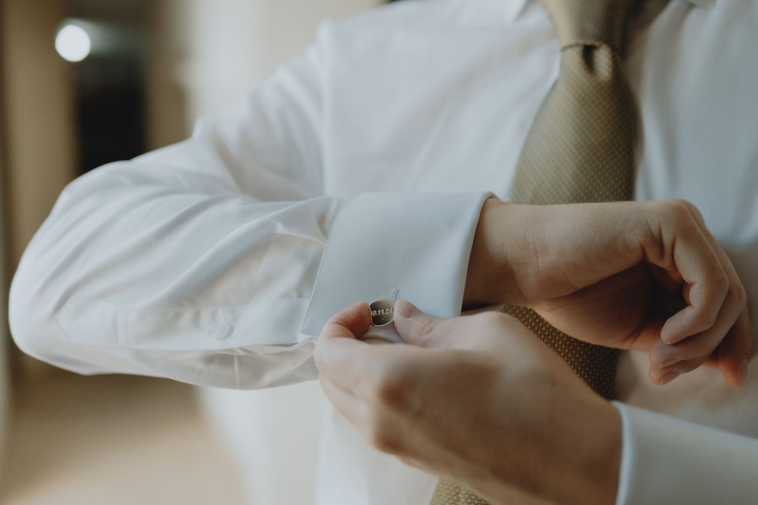 Close-up shot of groom adjusting cufflinks while getting ready.