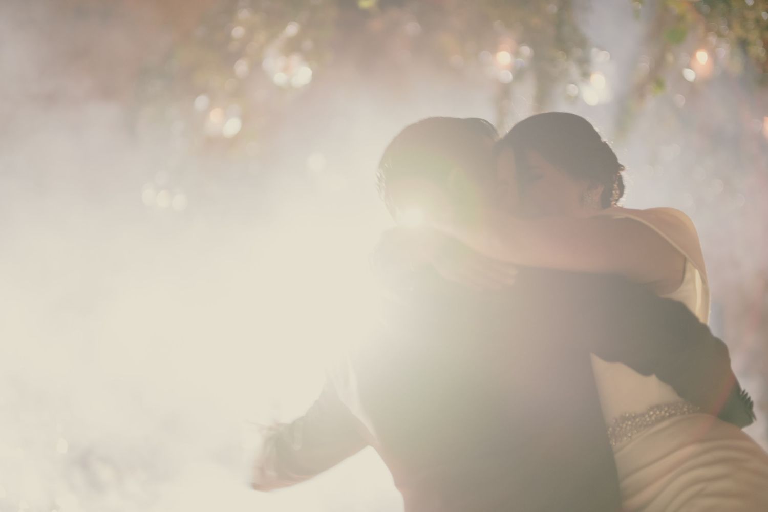 Romantic silhouette of newlyweds embracing in dreamy sunlit setting.