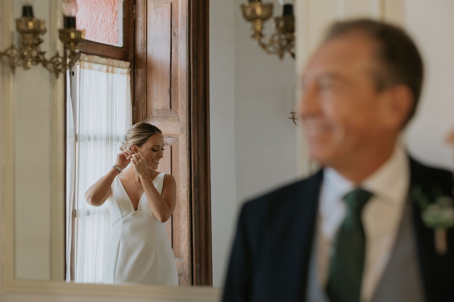 Emotional wedding moment captured in mirror reflection with elegant interior decor.