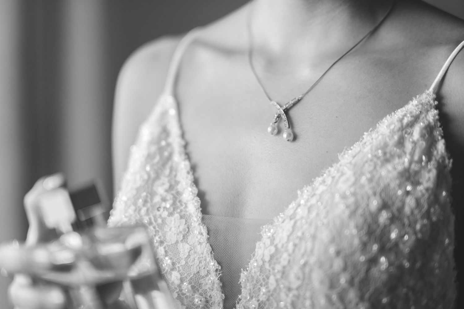 Close-up detail of a beaded wedding dress neckline and delicate necklace.