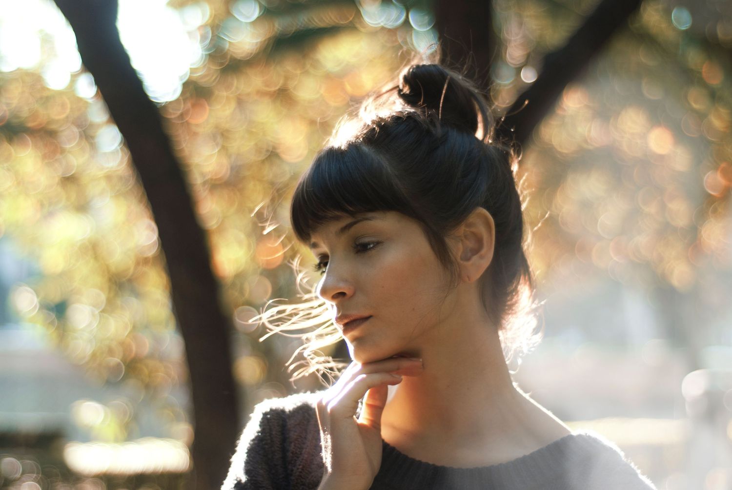 Dreamy portrait in warm sunlight with bokeh effect through trees.