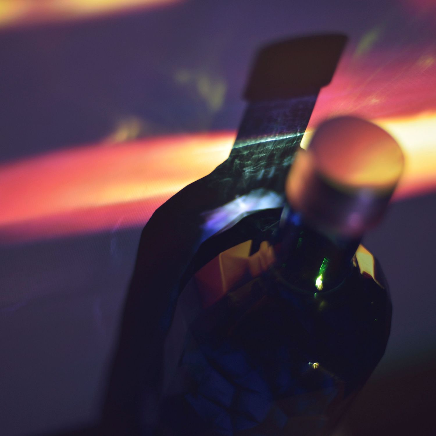 Artistic macro photography showing colorful light reflections with purple and orange hues creating an abstract pattern.