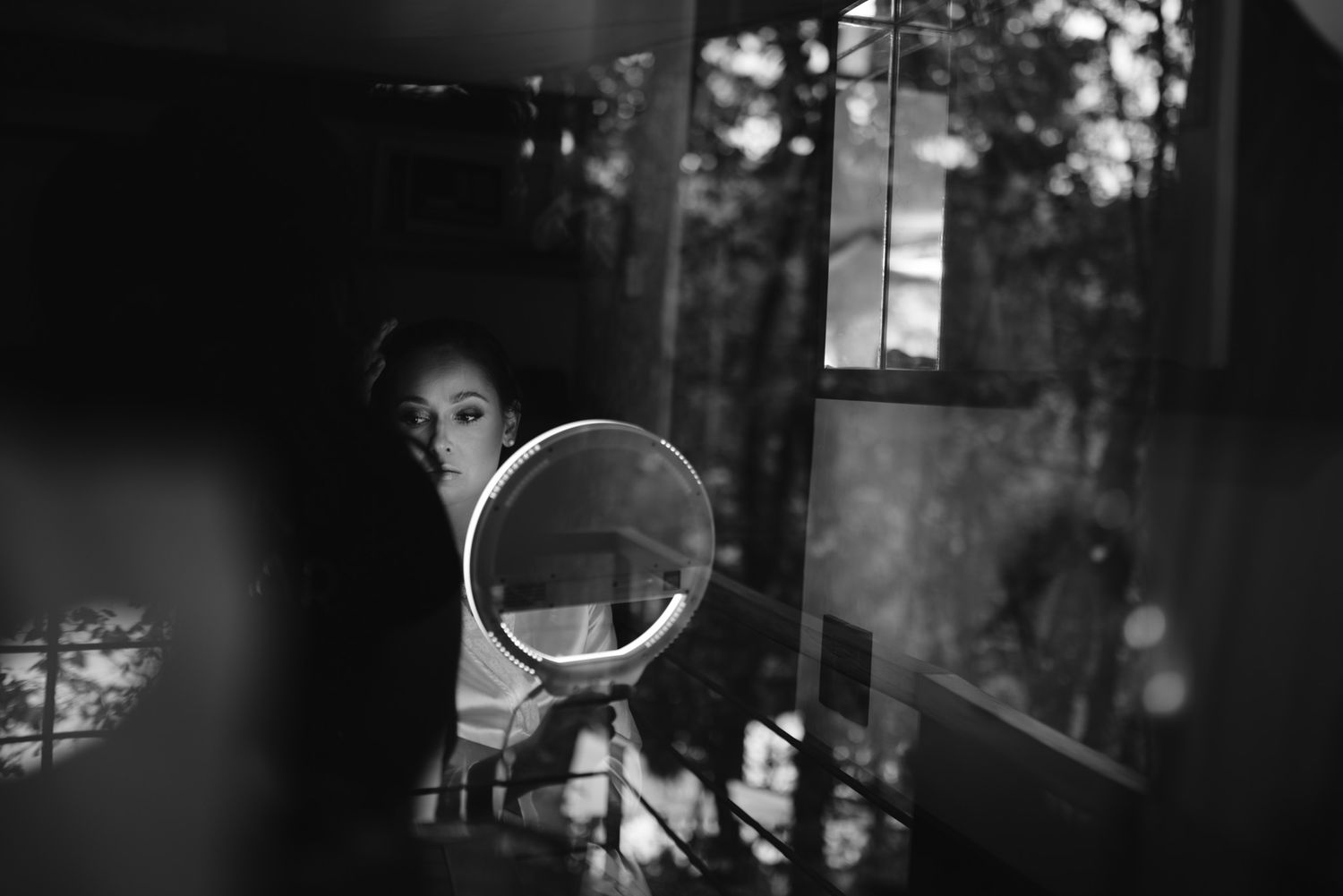 A moody black and white image showing a reflection in a circular mirror against a dark, shadowy interior.