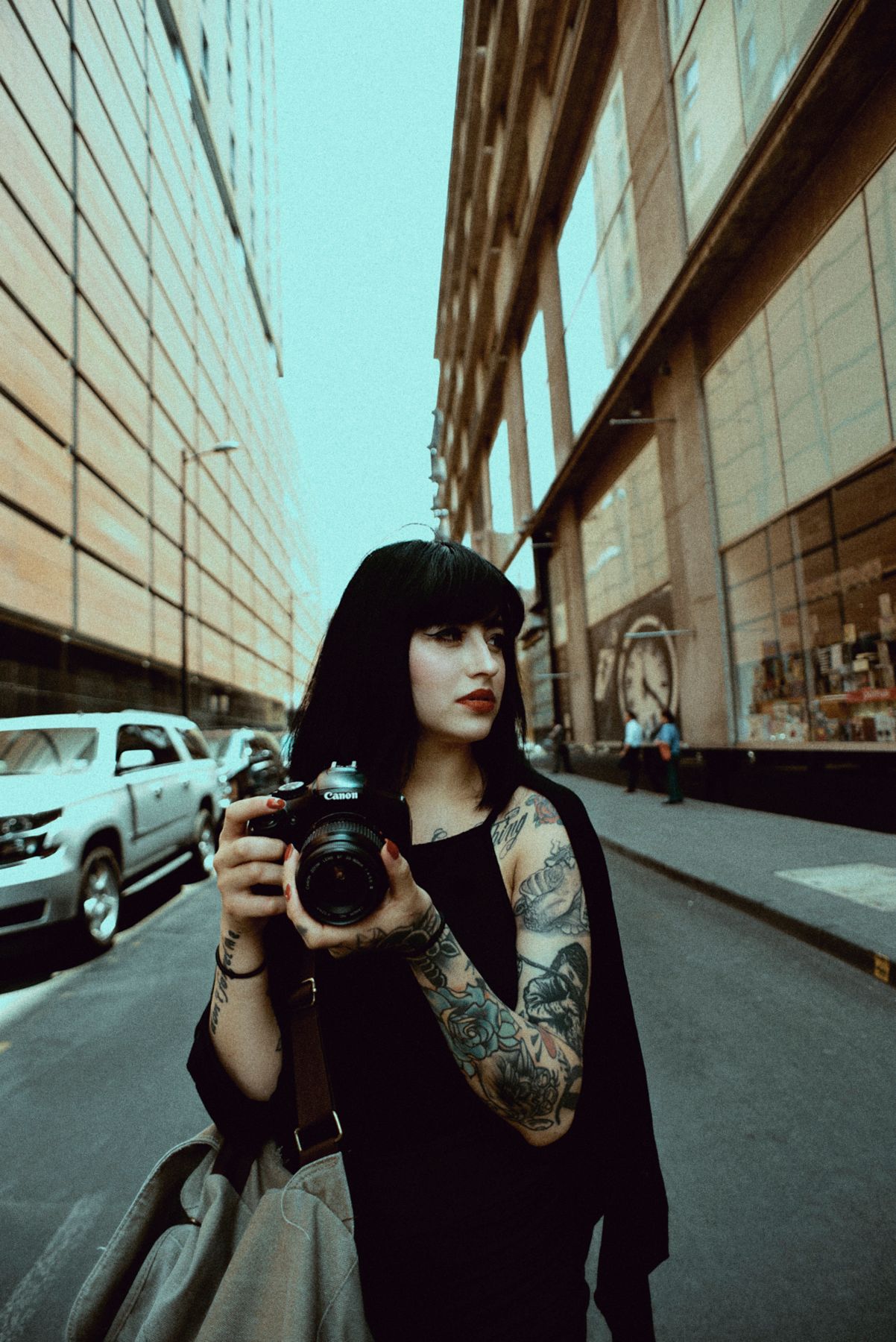 Tattooed photographer with camera in urban street setting.