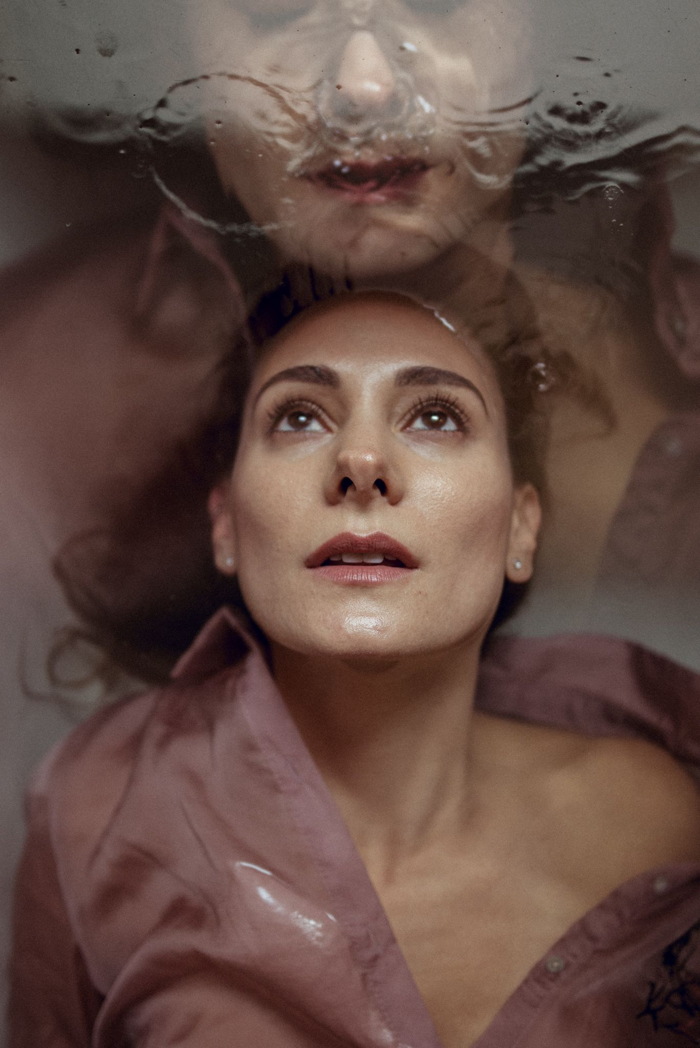 Artistic underwater portrait with dramatic lighting and pink fabric.