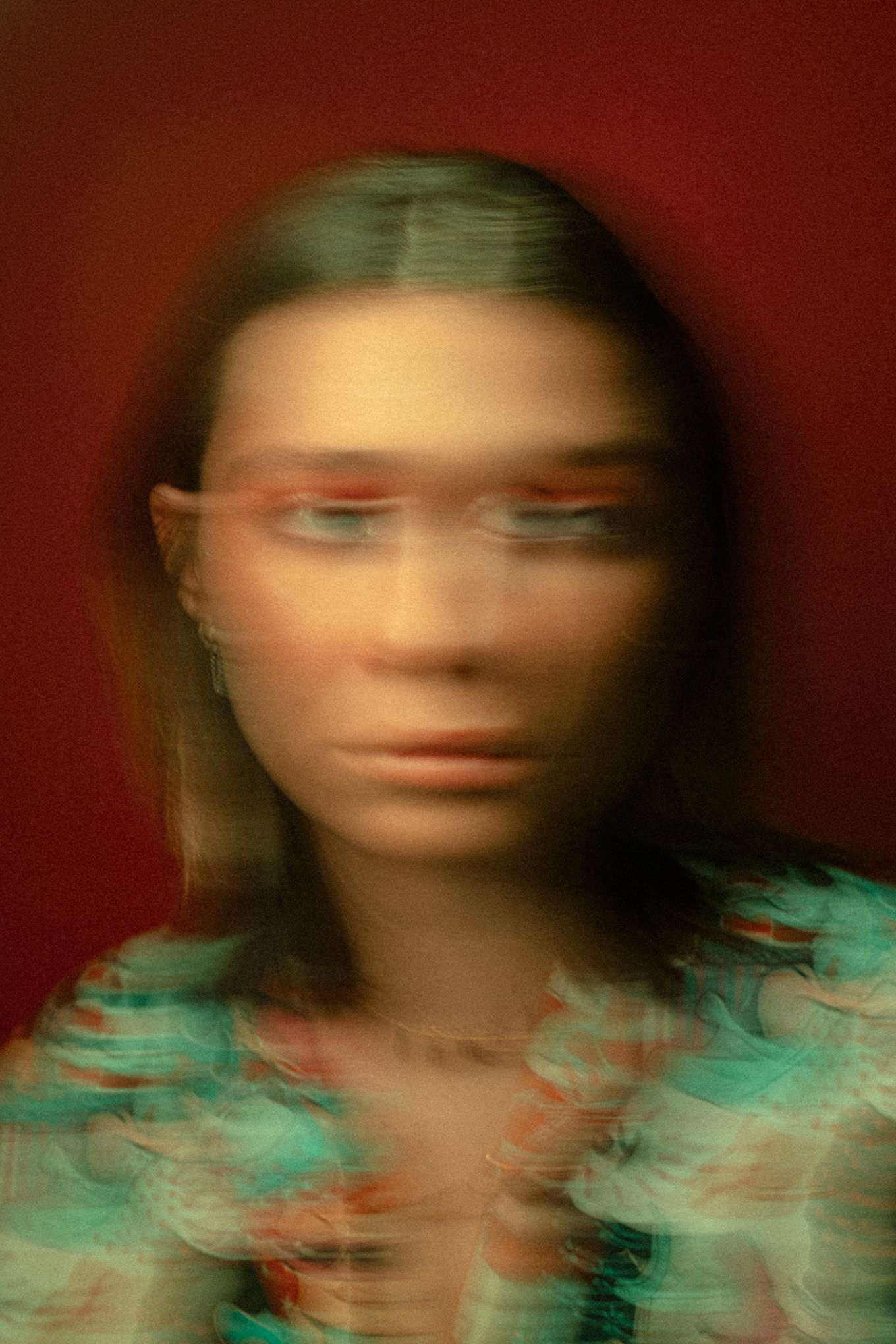 Abstract motion blur portrait with teal and red color palette against dark background.