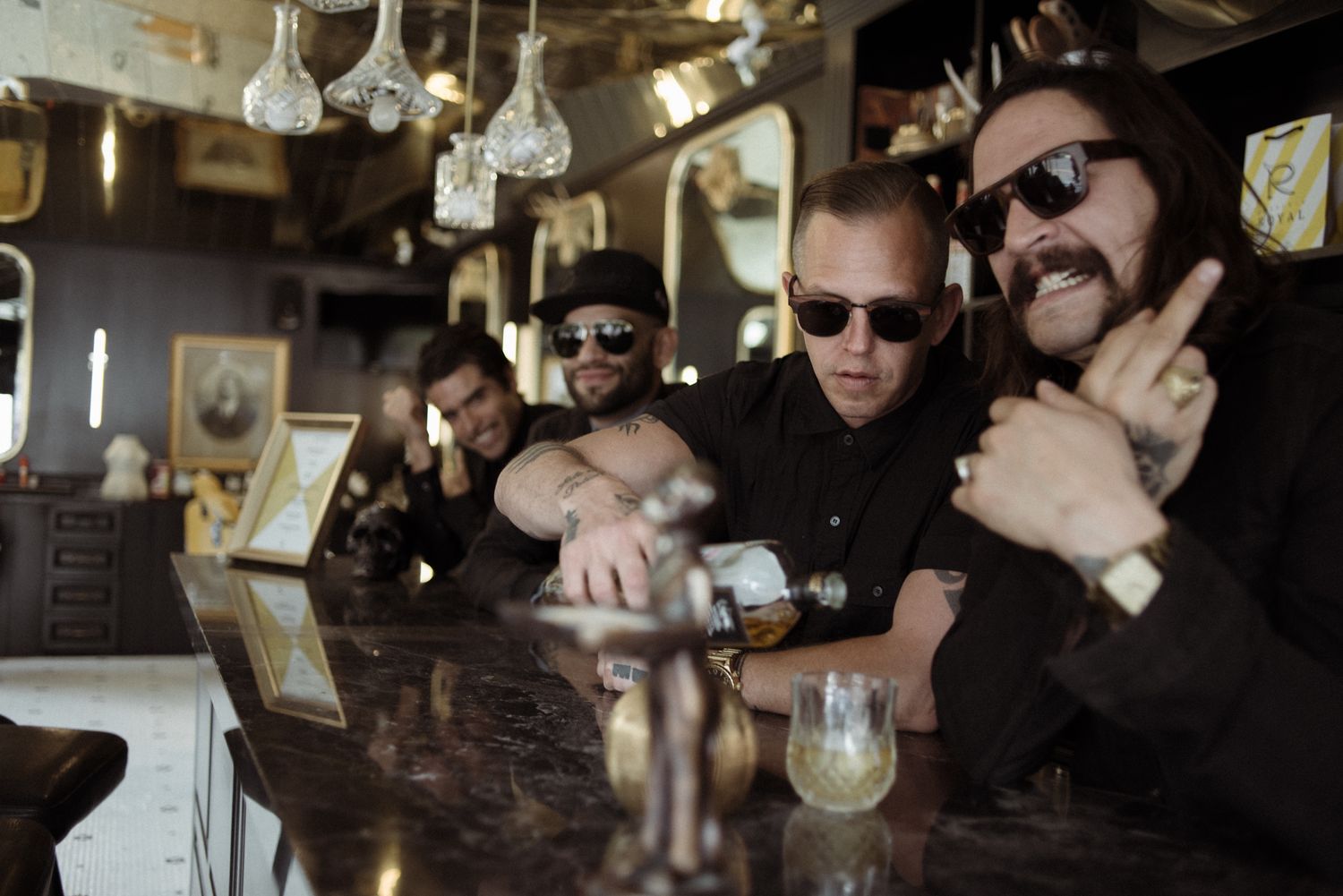 Group enjoying drinks together at a bar with hanging glasses visible overhead.