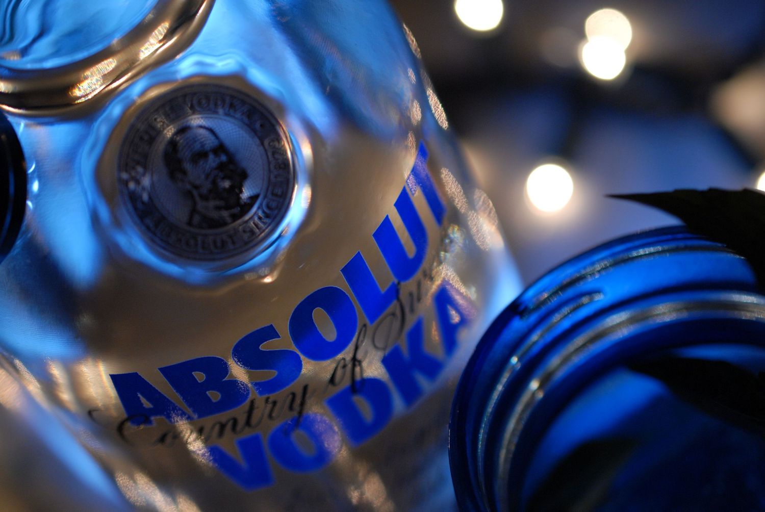 Artsy macro shot of Absolut Vodka bottle showing blue-tinted logo and reflections.