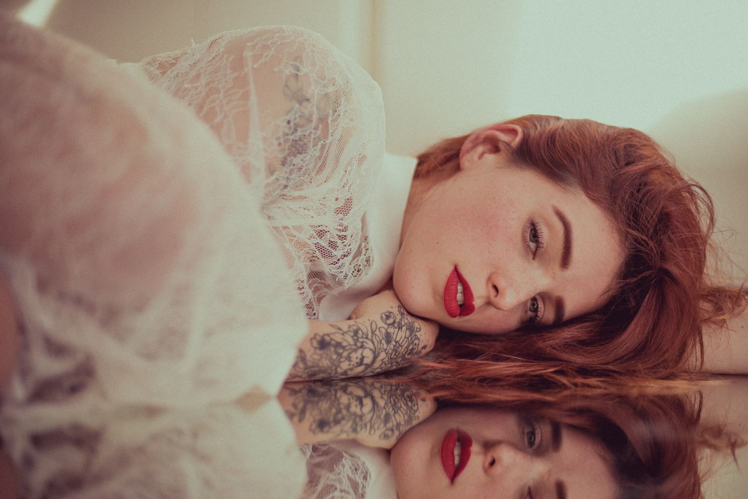 Romantic boudoir portrait with lace details and mirror reflection.