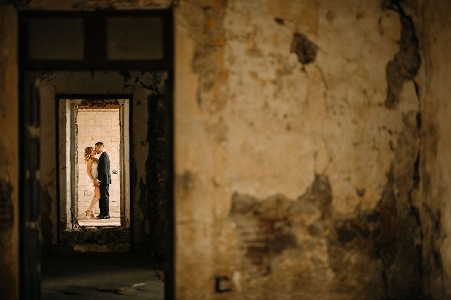 Artistic wedding photo framed through doorways of rustic stone building.