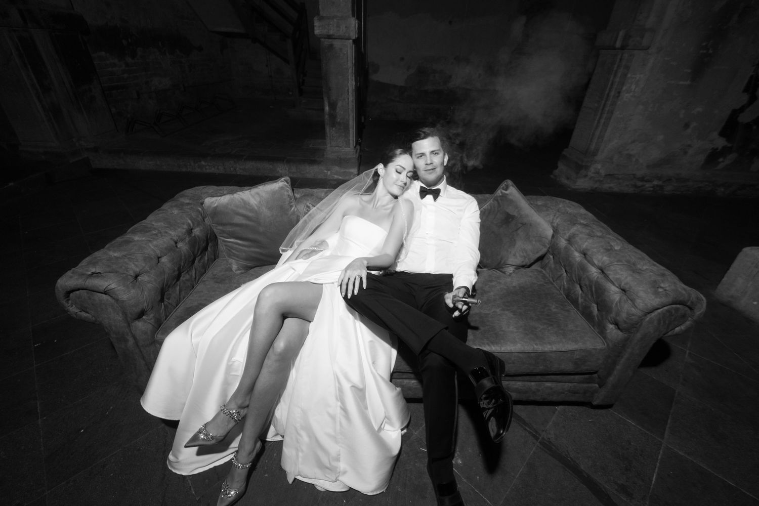 Black and white photo of newlyweds relaxing together on vintage couch.