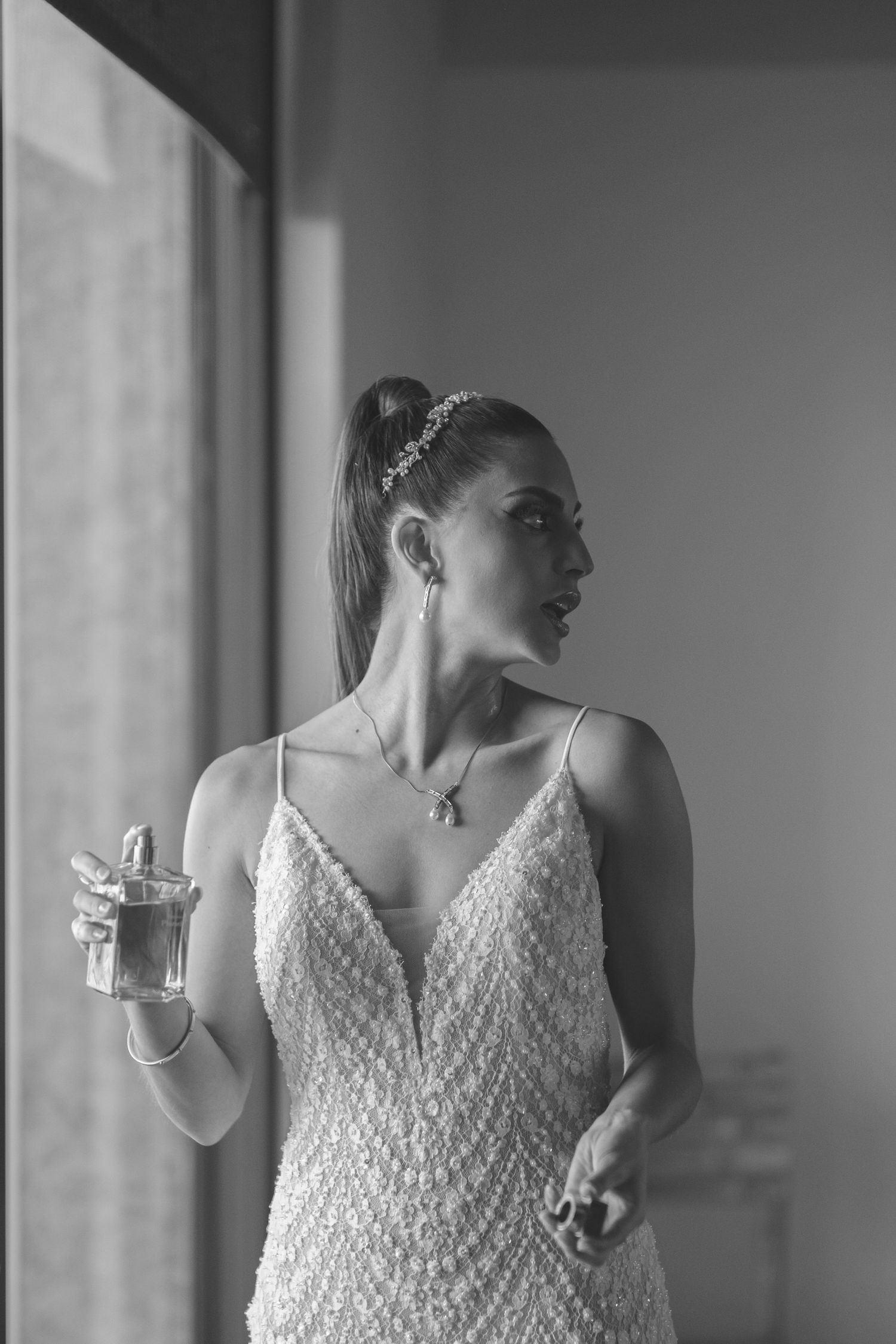 A wedding preparation moment showing a beaded dress and perfume bottle in black and white.
