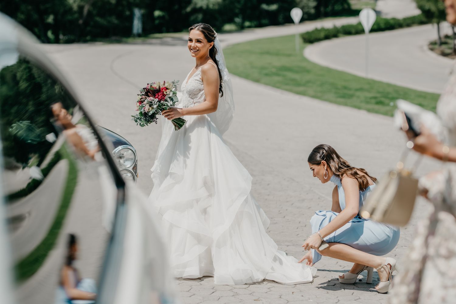 Wedding day preparation captured in motion with flowing white gown and elegant bouquet on a winding garden path.