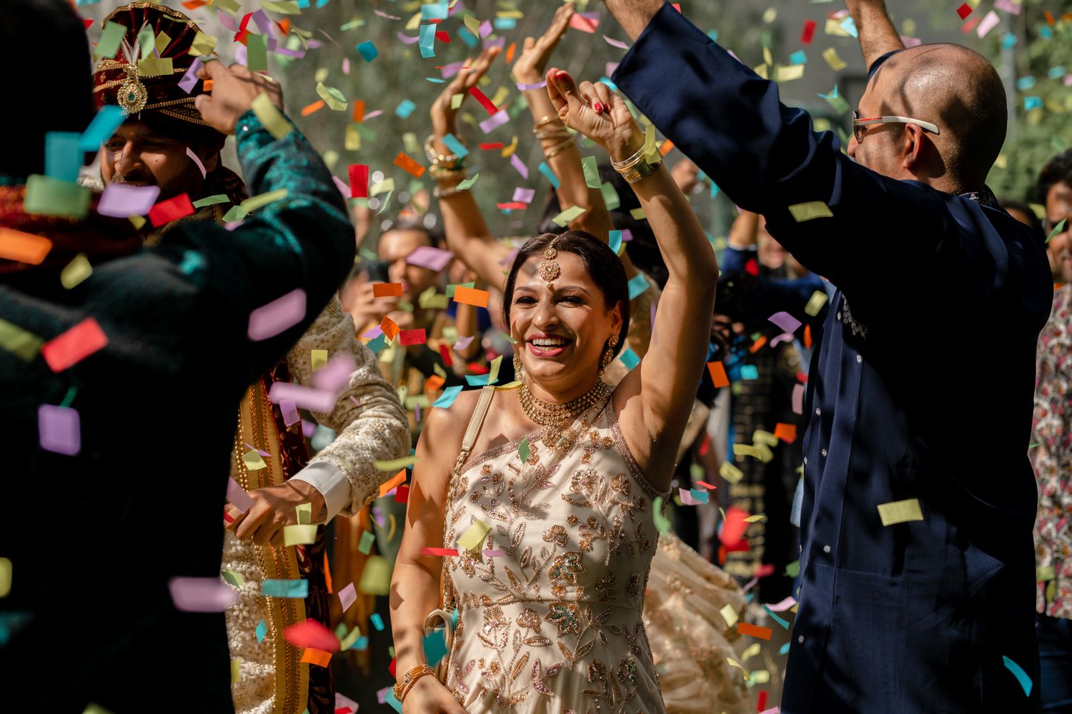 A happy couple celebrates their wedding day with colorful confetti raining down during an outdoor ceremony.