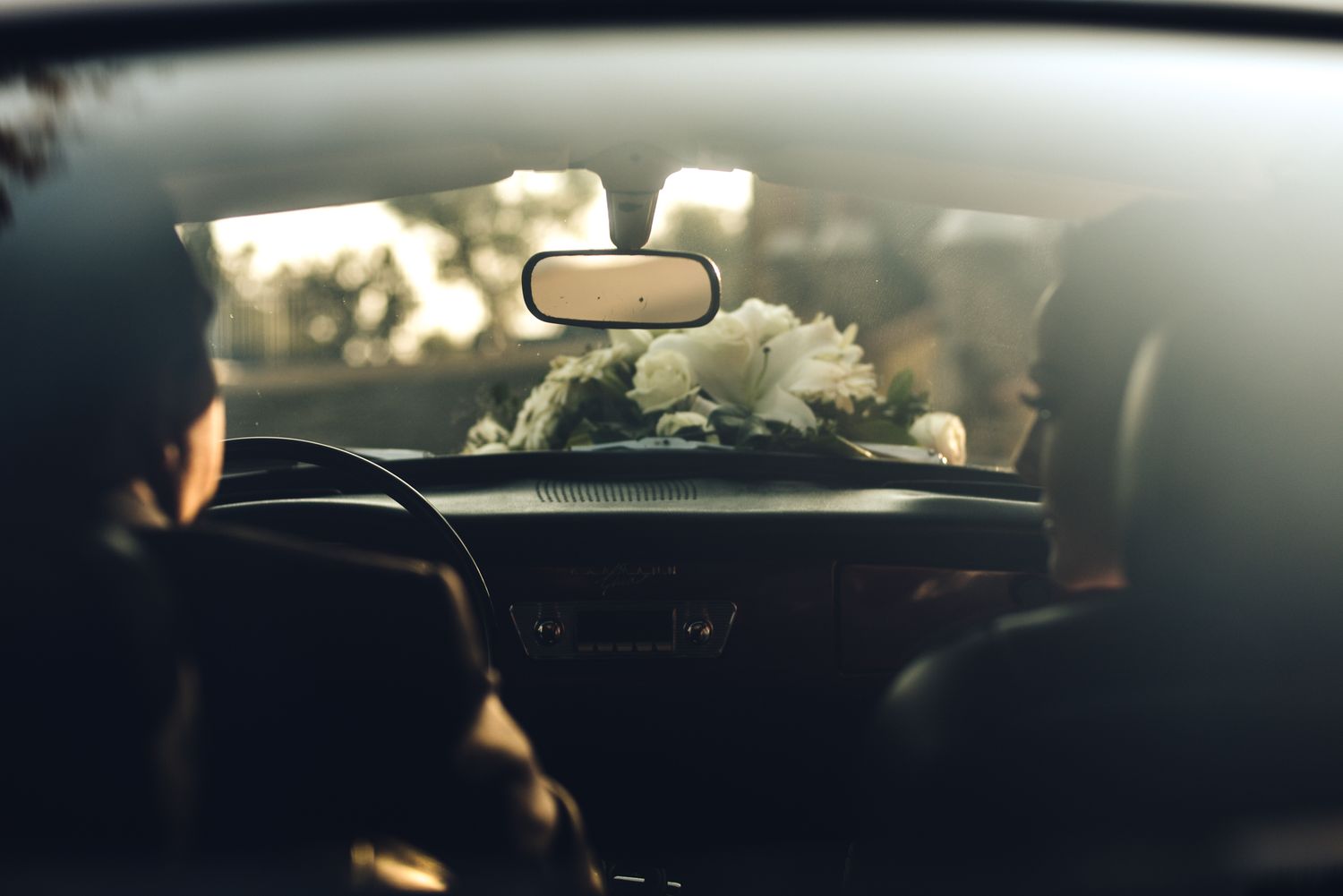 View through car windshield on sunny day with rearview mirror and dashboard visible.
