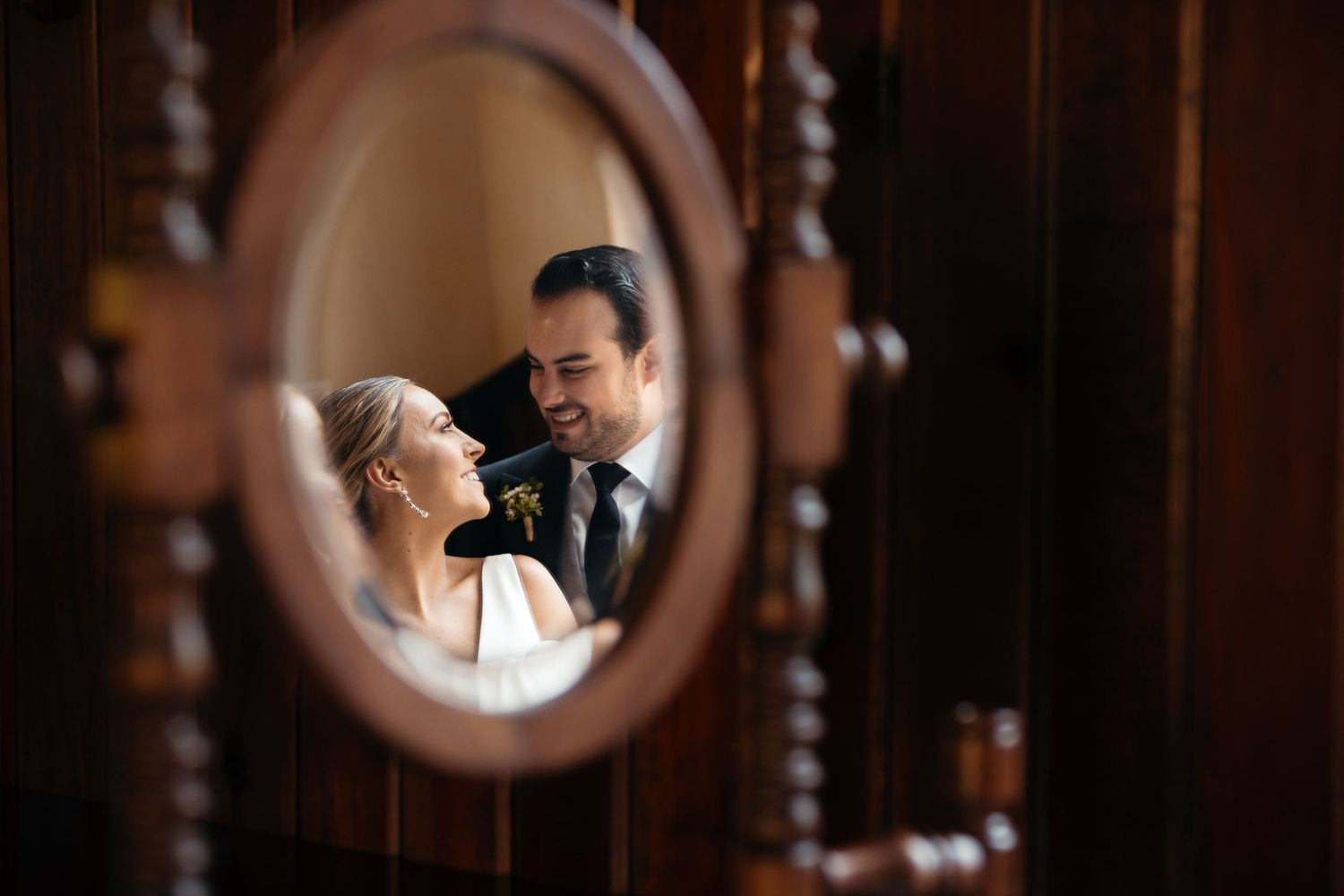 A romantic reflection of a couple in a vintage mirror shows an intimate wedding moment.