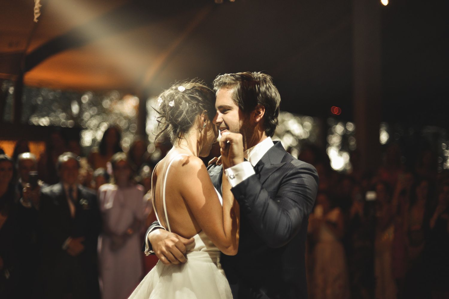 Romantic first dance moment under dramatic lighting at wedding reception.