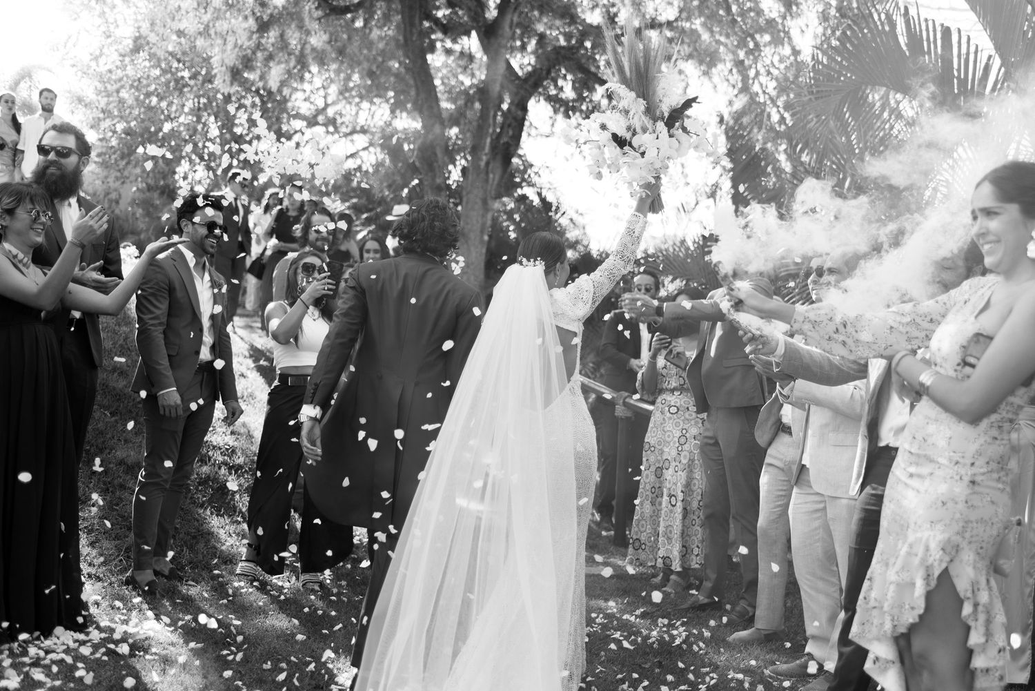 Black and white celebration scene with confetti shower at outdoor wedding ceremony.